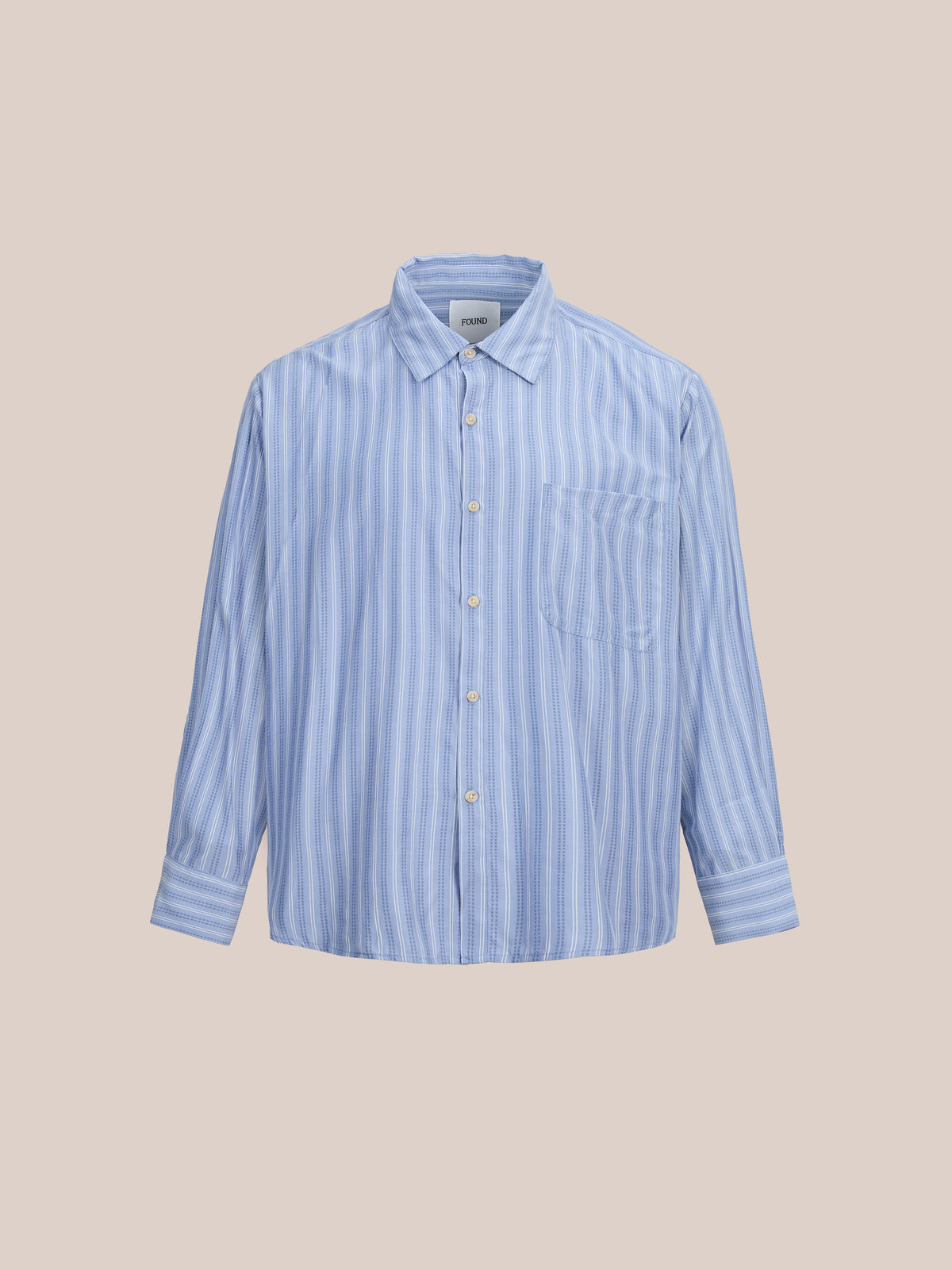 The FOUND Stripe Pocket Oxford Shirt features a light blue and white stripe, unisex relaxed fit, long sleeves, chest pocket, and is shown on a beige background.