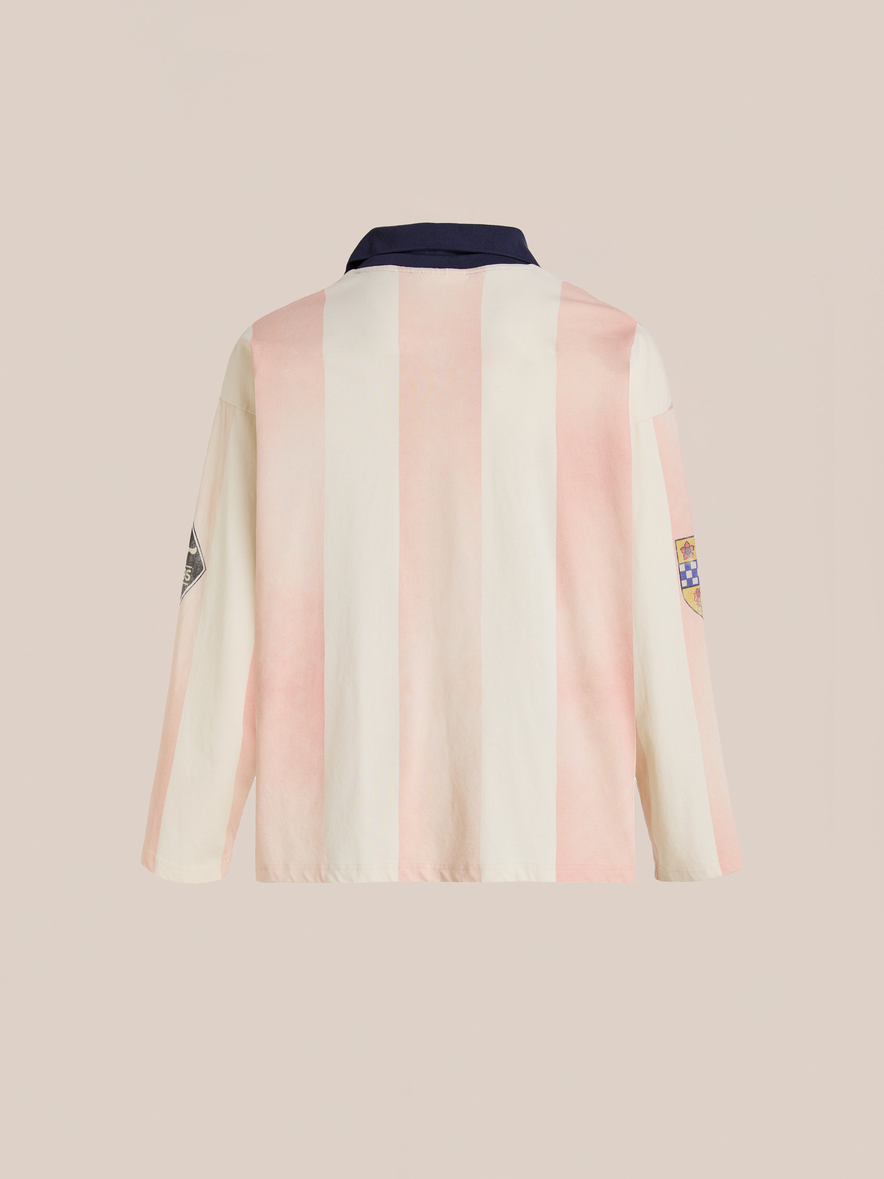 The FOUND Striped Sport LS Jersey features light pink and white vertical stripes, a dark collar, and sleeve patches. Shown from the back on a neutral background, its unisex relaxed fit captures a classic football silhouette.