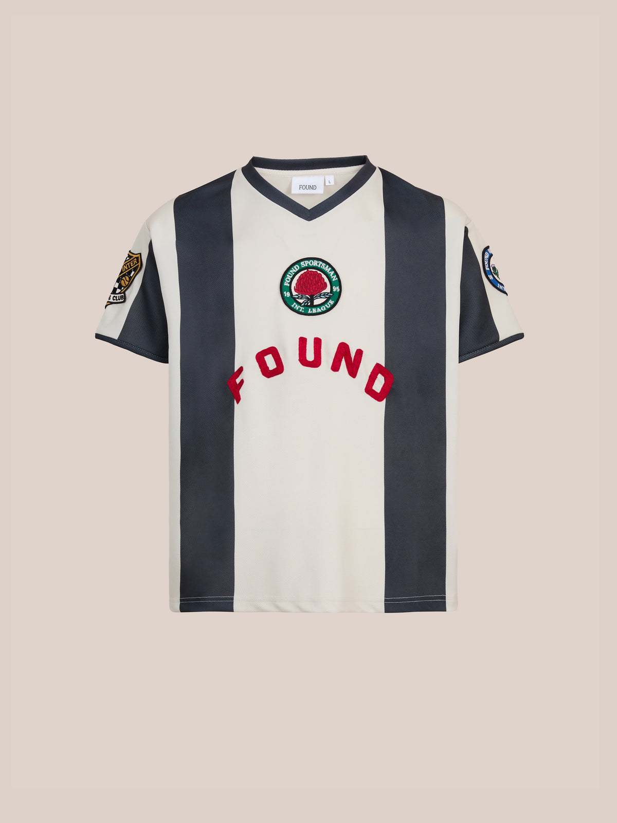 The Striped Stateman Jersey by FOUND features vertical black and white stripes, red “FOUND” text, and embroidered patches—classic unisex sportswear.