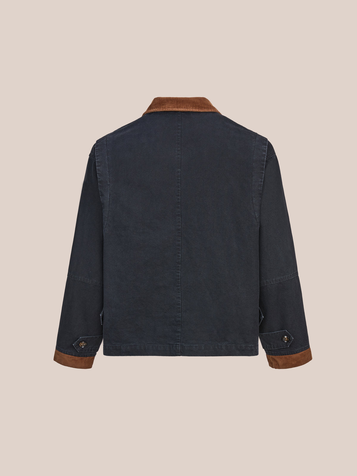 The Toggle Work Jacket by Found is shown from the back against a light beige background, highlighting its dark denim construction, brown corduroy collar and cuffs, long sleeves, and button details at the wrists. Inspired by classic vintage work jacket designs, this unisex relaxed fit piece combines timeless style with modern comfort.