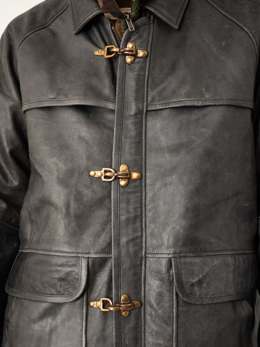 Close-up of the FOUND Distressed Leather Fireman Clasp Jacket, a unisex piece with three brass toggle clasps and two front pockets, crafted for enduring style in genuine leather.