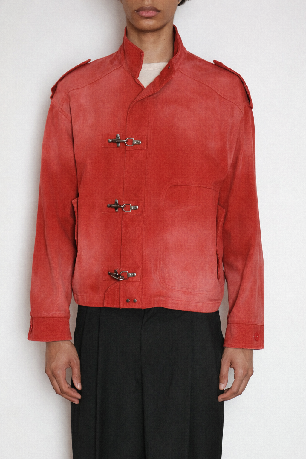 A person wears the FOUND Utility Clasp Work Jacket in vintage red with metal toggle closures and black pants, standing against a plain white background.