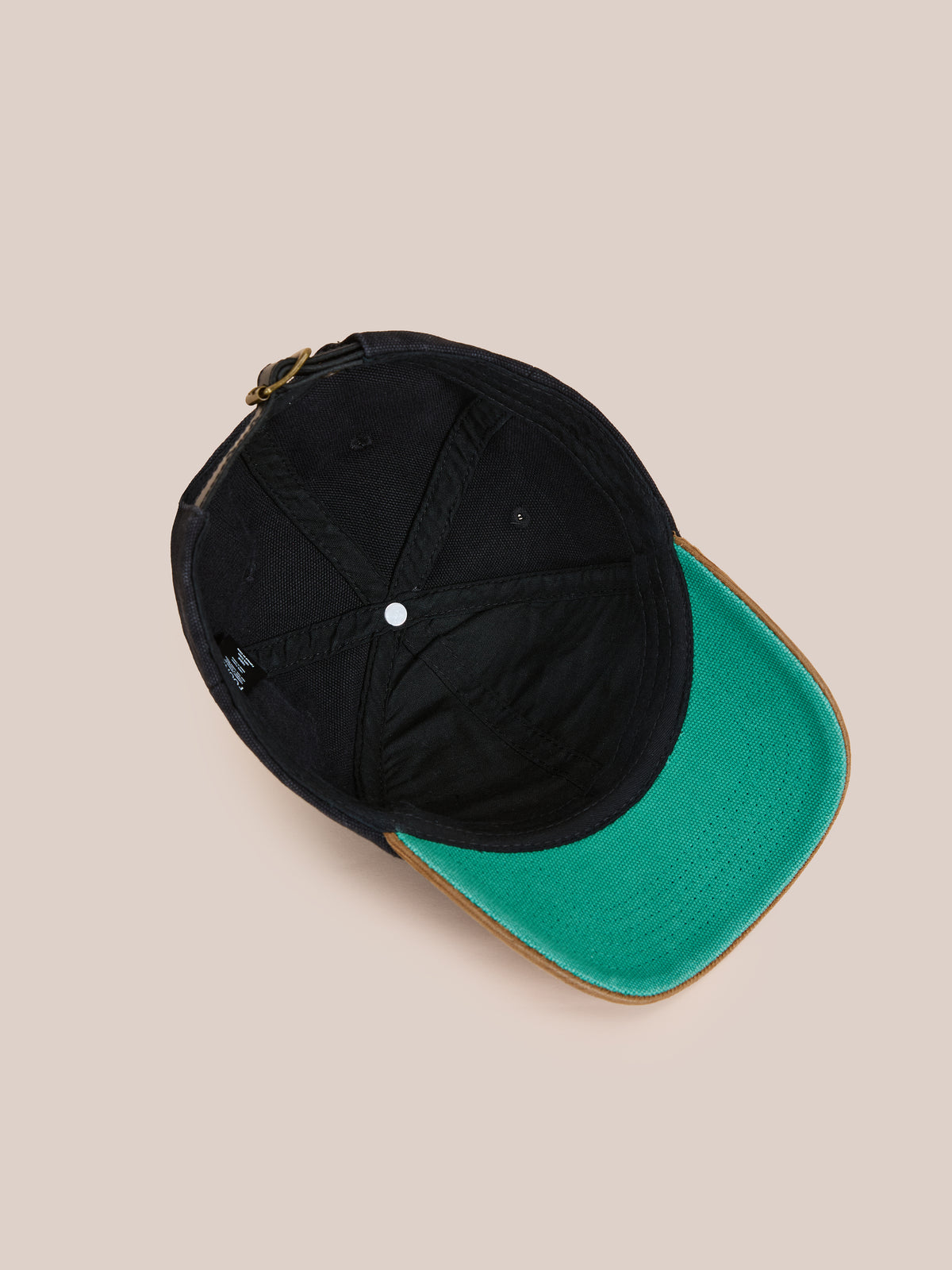 The Found Vintage Club Cap in black, shown from below, features vintage detailing, a green underside brim, and an adjustable back strap.