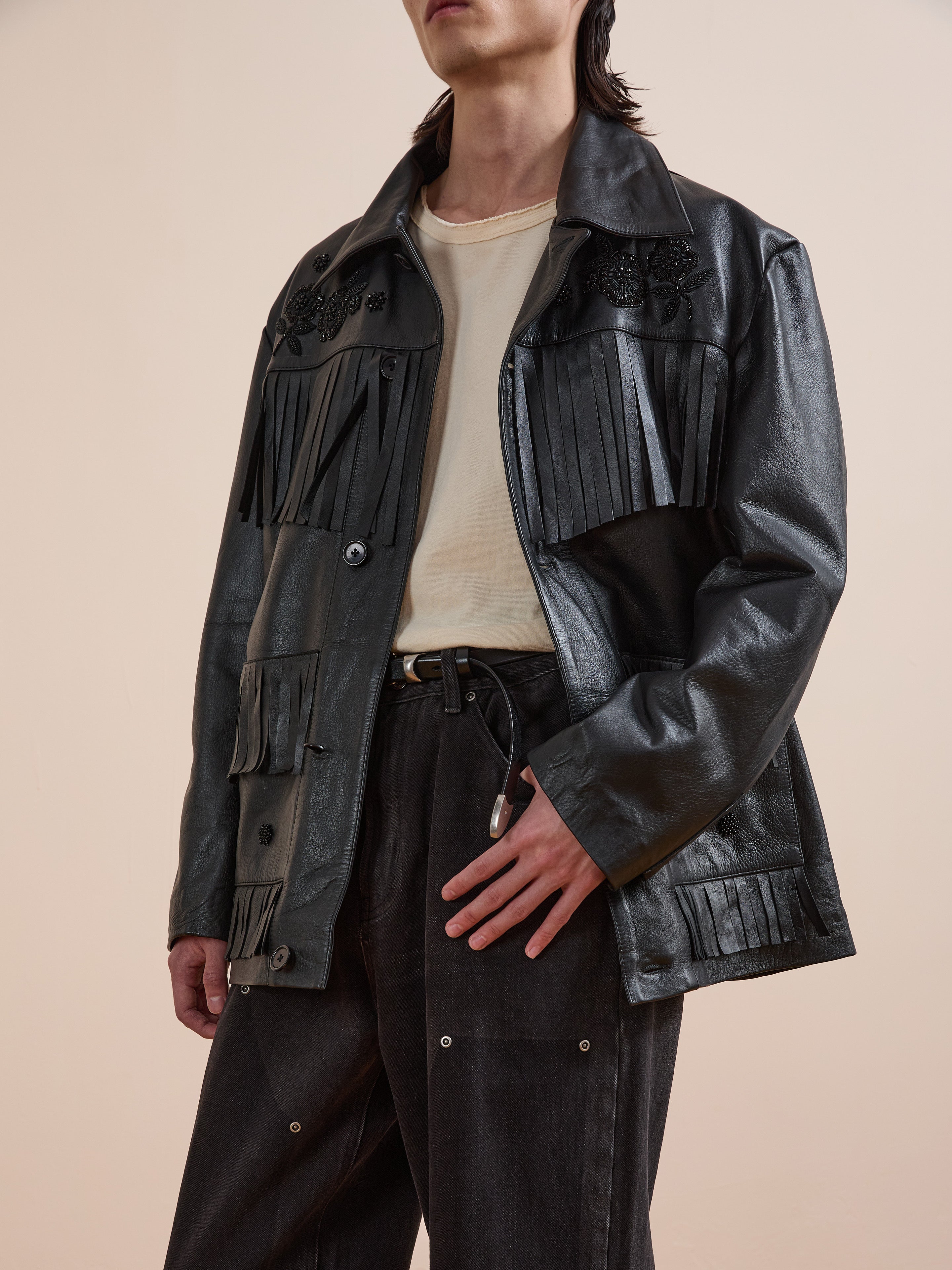 A person wears the FOUND Hand Embroidered Leather Fringe Jacket over a beige shirt and black pants, standing against a plain background.