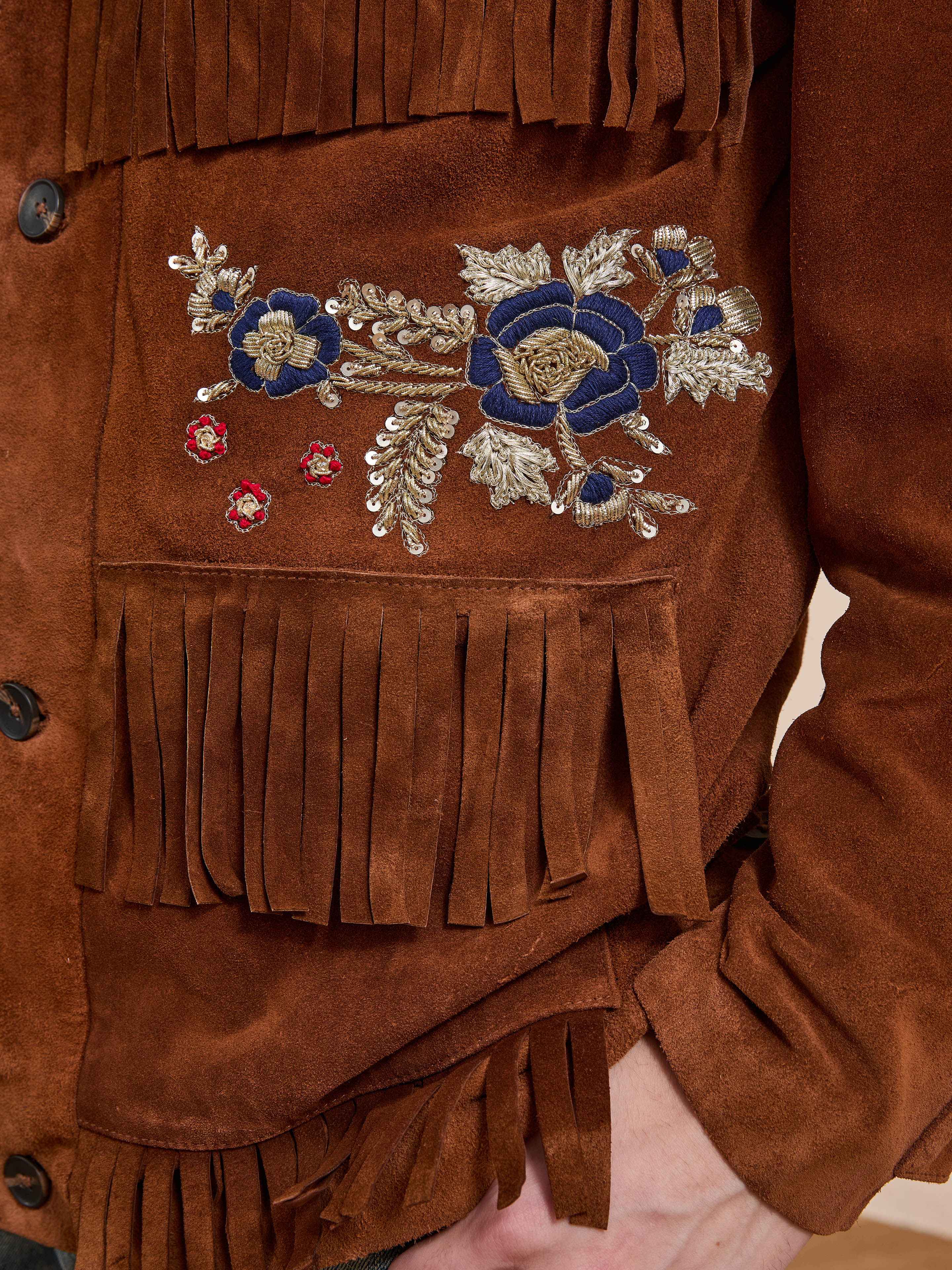 FOUND’s Hand Embroidered Suede Fringe Jacket features blue and gold floral embroidery on the chest—a standout unisex piece with classic Western fringe.