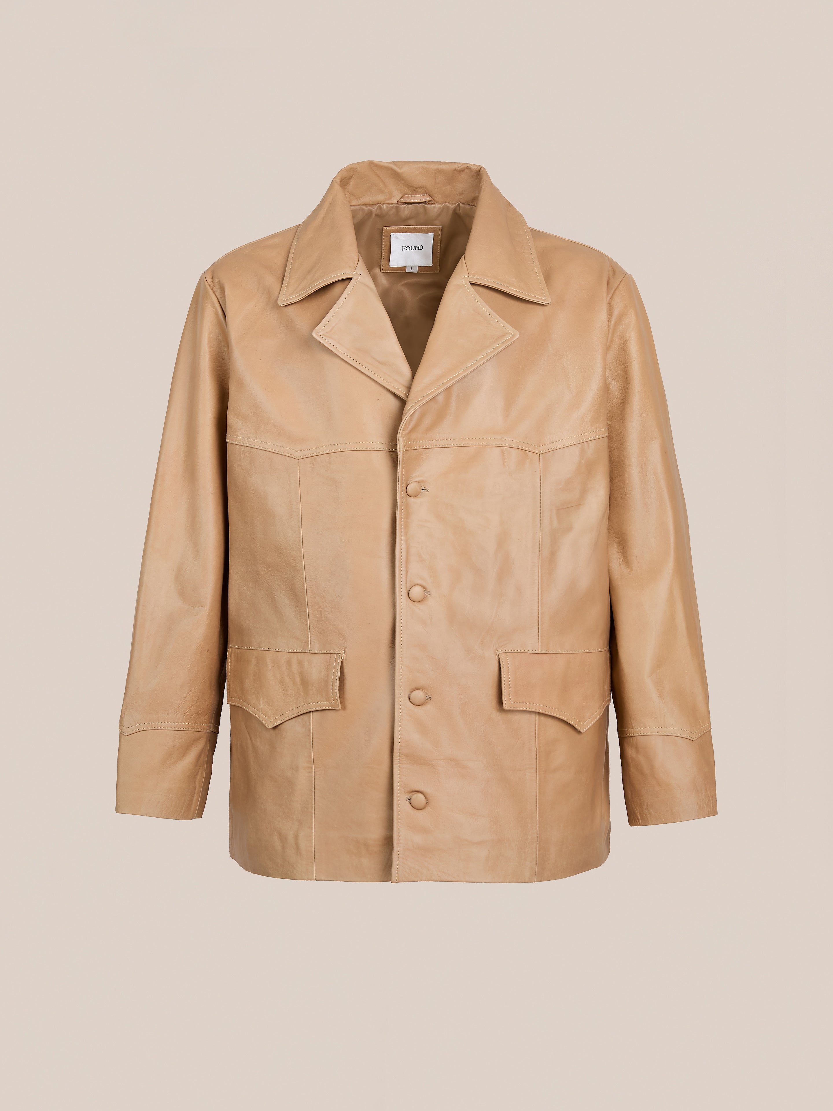 The FOUND Western Oversized Leather Blazer features camel-colored leather, a notched collar, front buttons, long sleeves, and two large front pockets in an oversized fit, shown against a plain beige background.