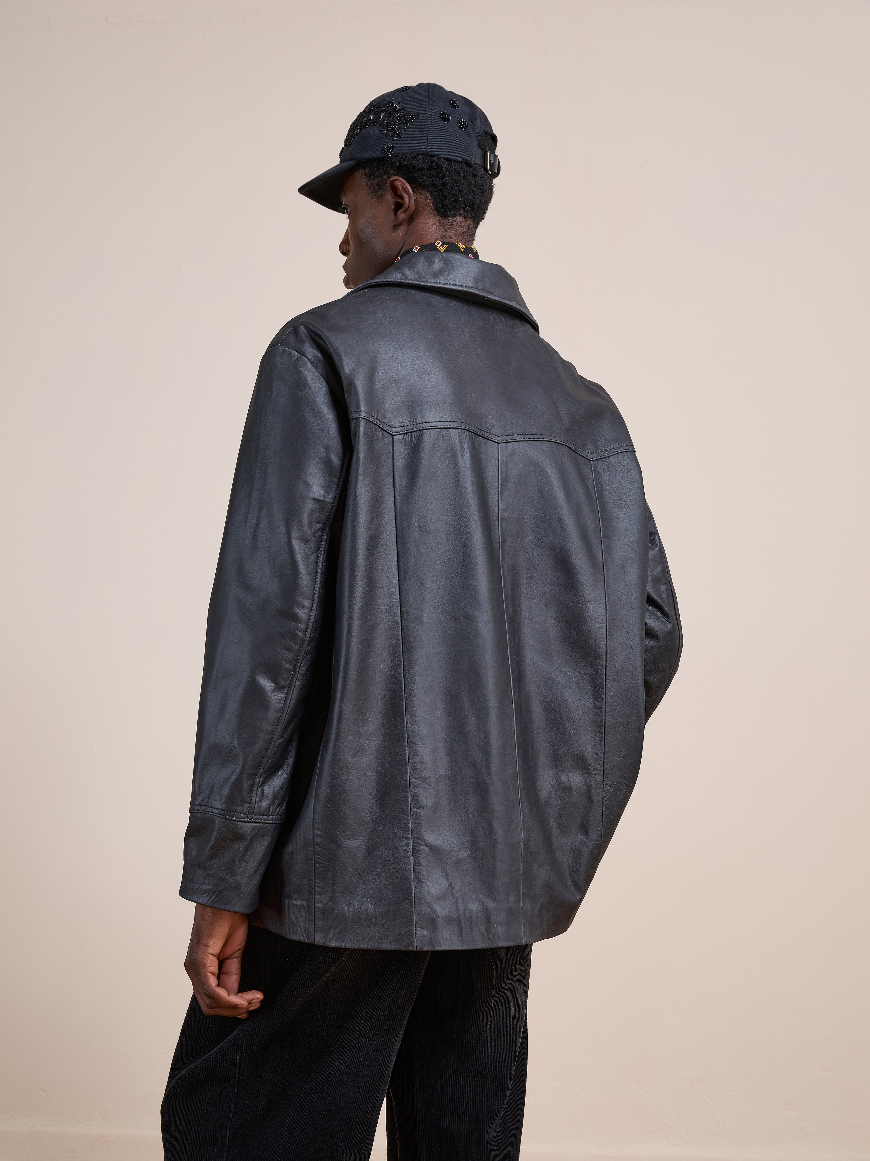 A person shown from the back wears the FOUND Western Oversized Leather Blazer, paired with black pants and a black cap, set against a plain light background.
