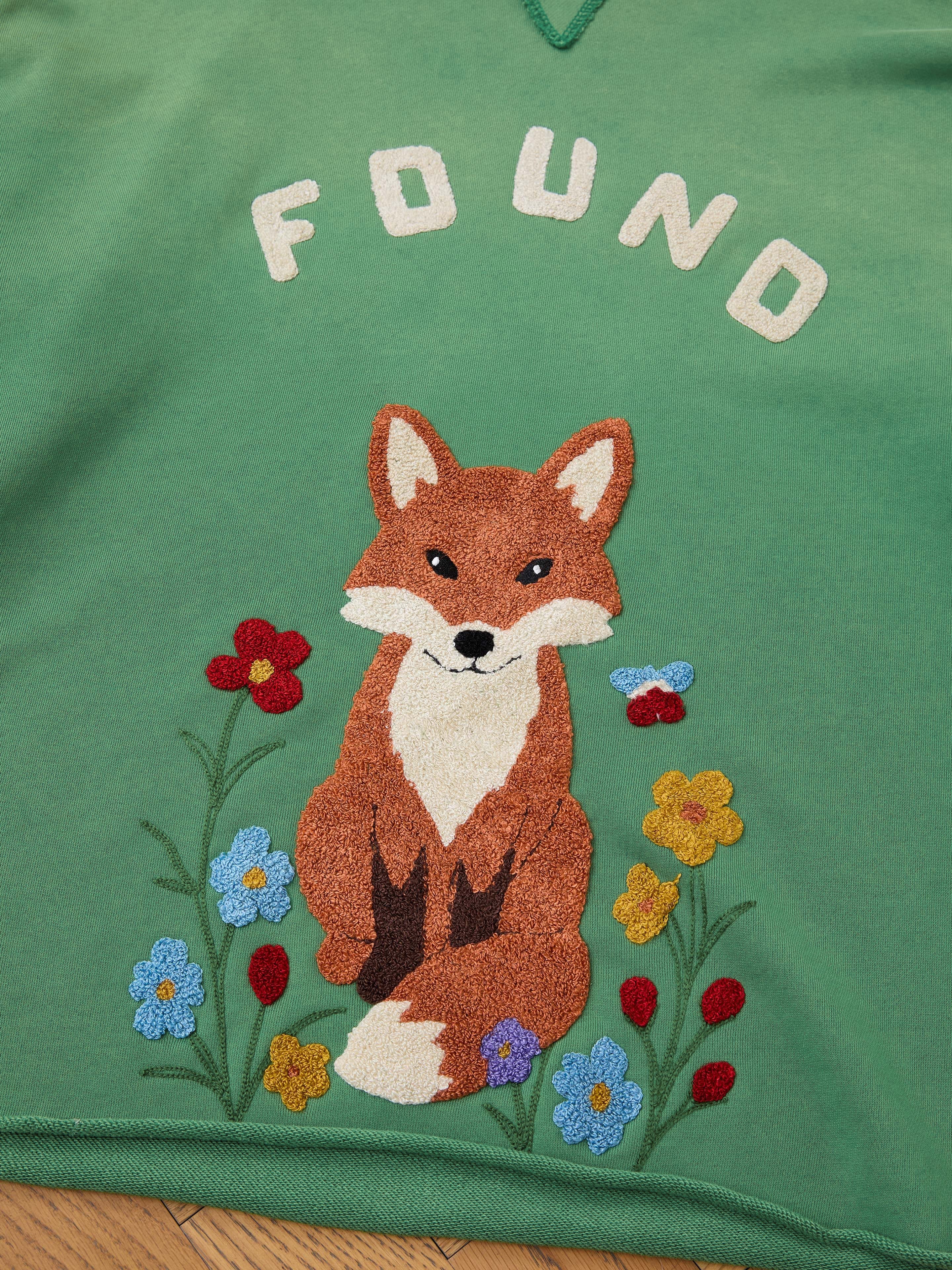The Embroidered Wildlife Hoodie by FOUND is a green French-terry cotton unisex hoodie, featuring a relaxed fit and an embroidered fox among colorful flowers with "FOUND" stitched above—perfect for nature lovers.