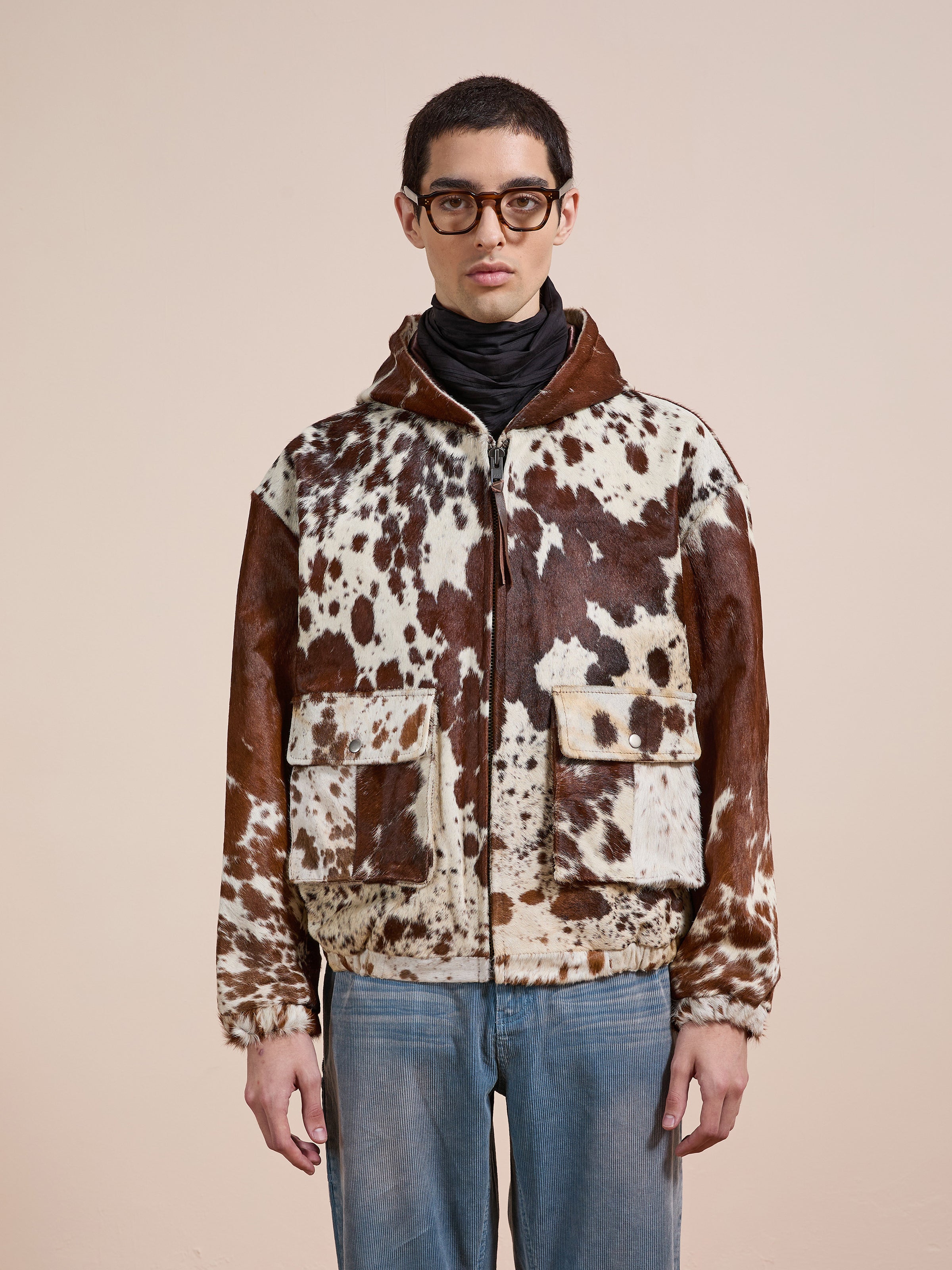 A person wearing glasses and the FOUND Cowhide Drover Hoodie stands facing forward against a plain beige background.