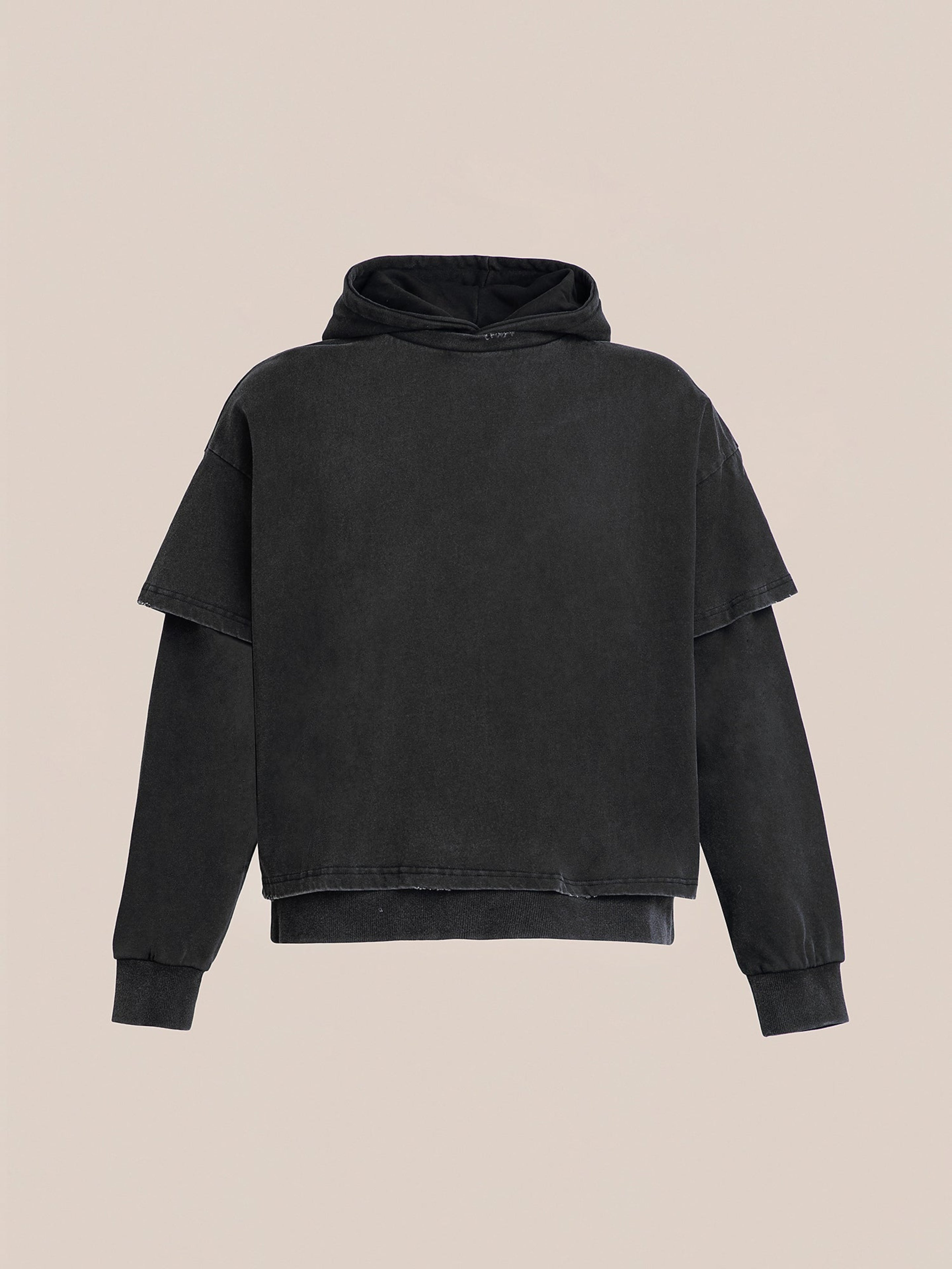The Double Layer Hoodie by Found is a black, French terry cotton hoodie showcasing a vintage design with its short sleeves over long ones, set against a plain background.
