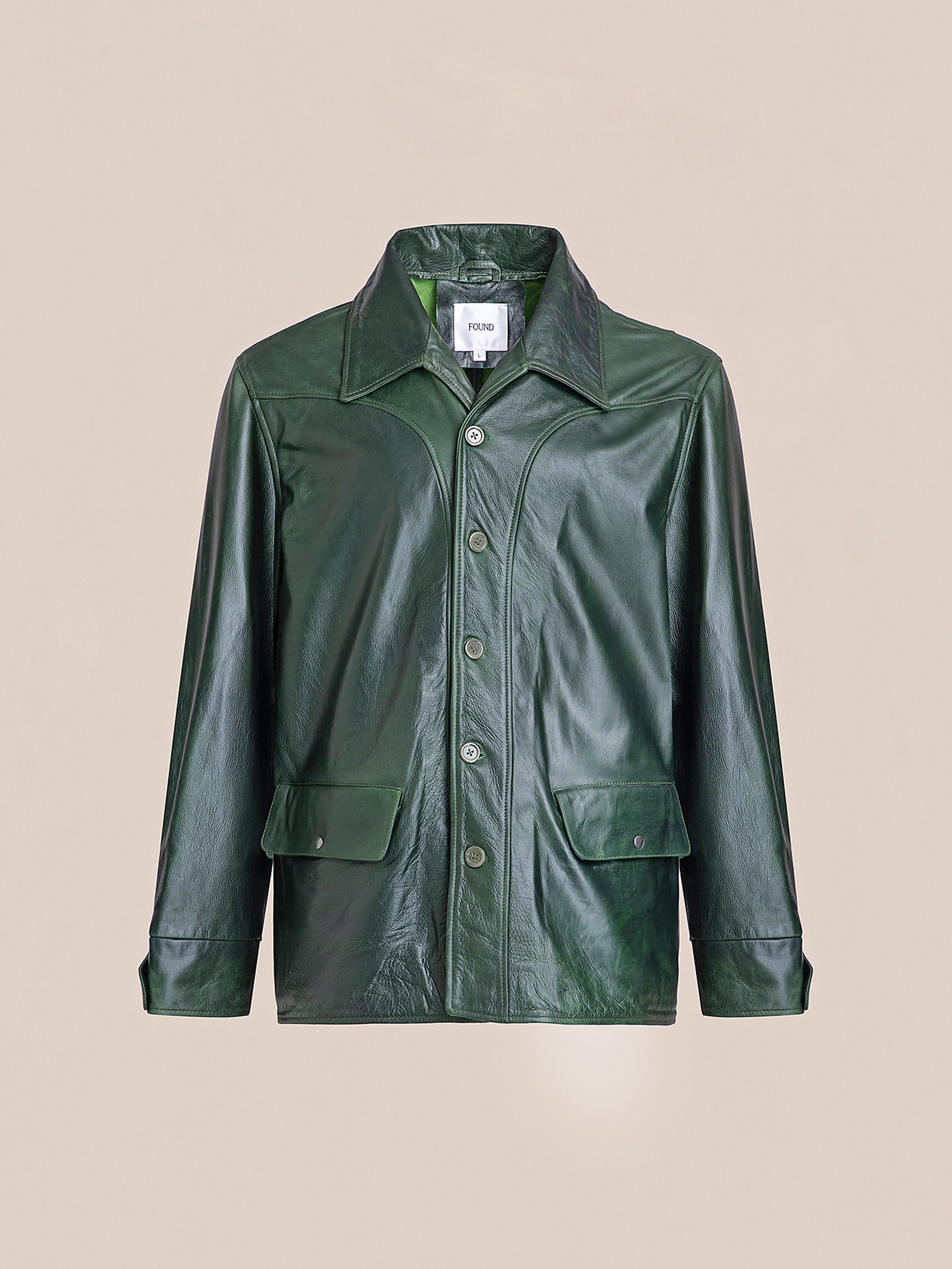 FOUND Leather Field Jacket in emerald green, made from ethically sourced, hand-distressed leather, with a collar, front buttons, and two flap pockets, shown against a plain beige background.