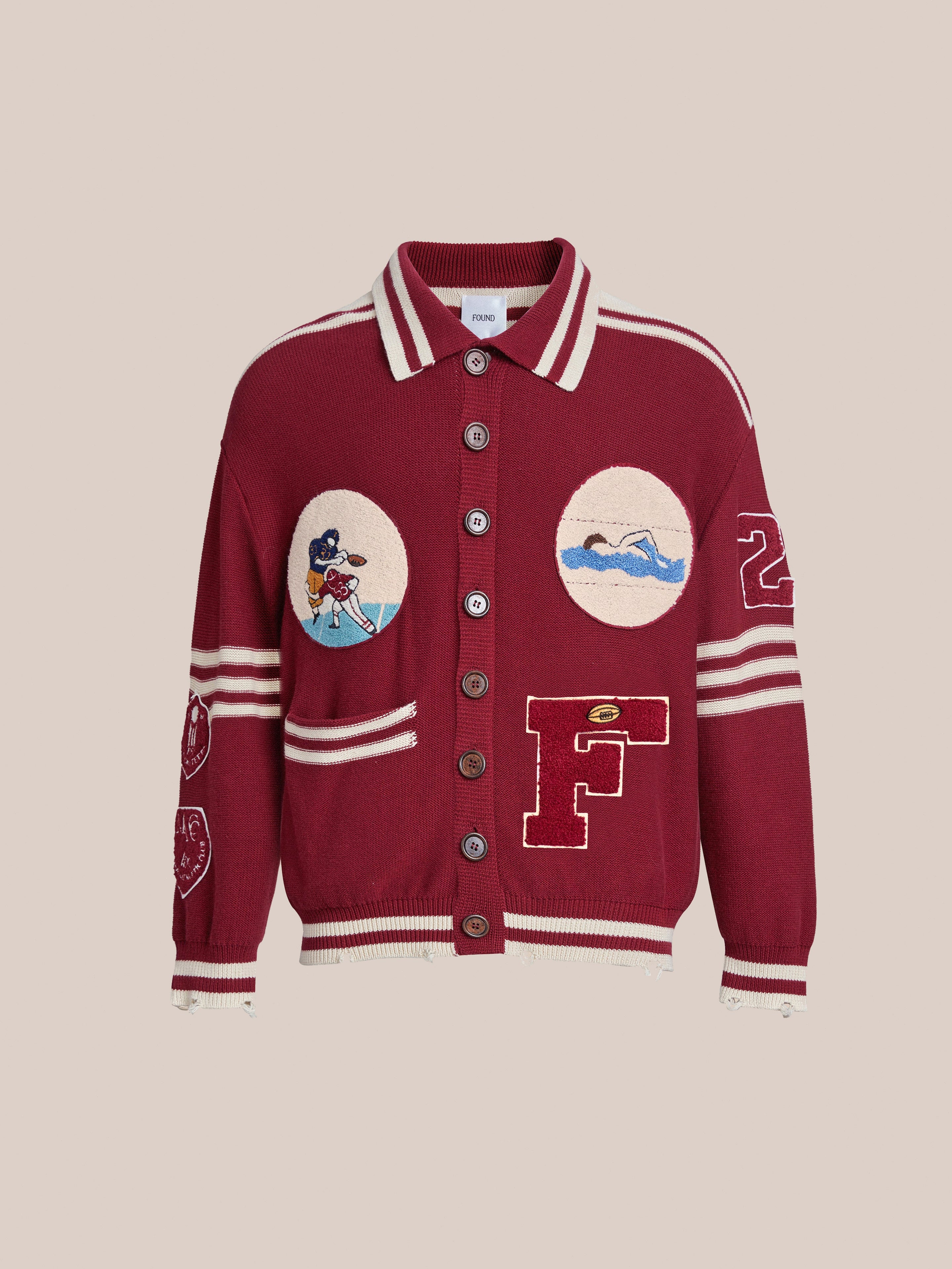 The Fin Varsity Patch Collared Cardigan by Found is a vintage-inspired piece with a red button-up design, white stripes, patches of a swimmer, baseball player, and the letter "F," plus the number 22 on the sleeve—ideal for an Ivy League wardrobe.