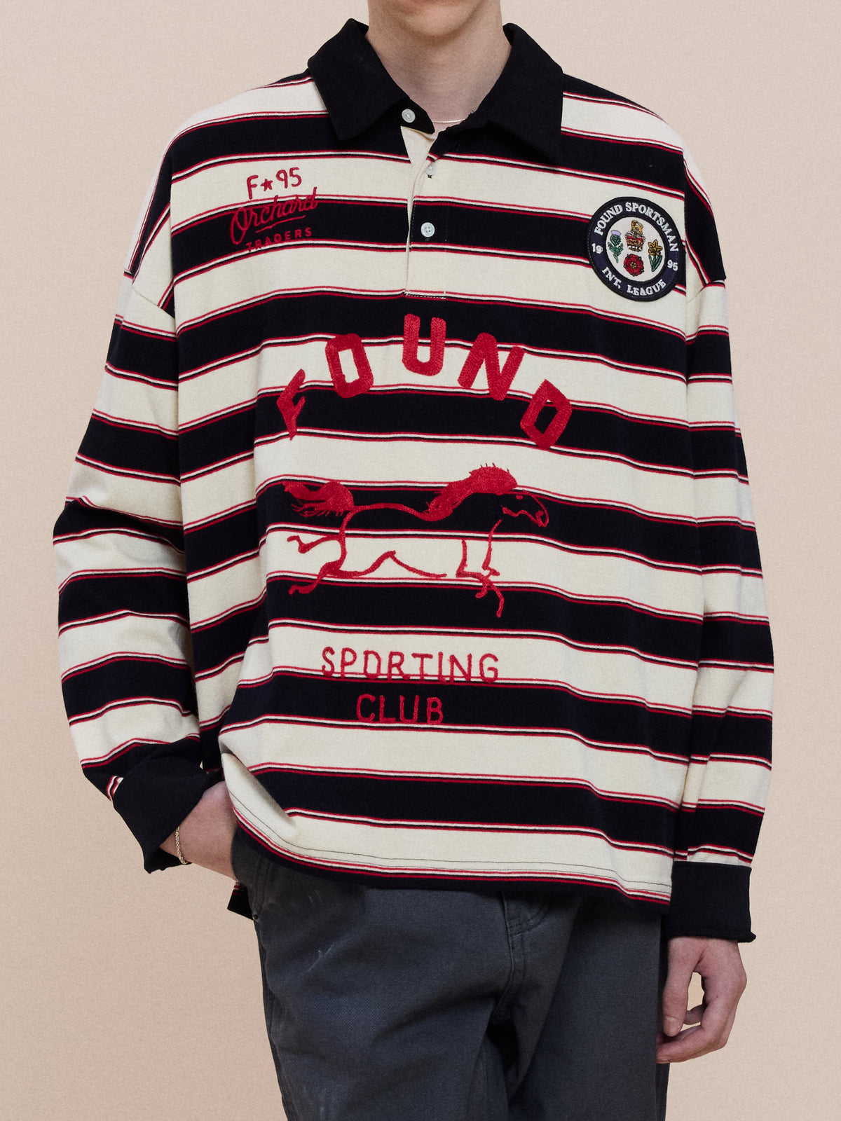 Person in the FOUND Horse Logo Rugby featuring a horse graphic and “FOUND SPORTING CLUB,” paired with dark pants—a stylish nod to heritage athletics.