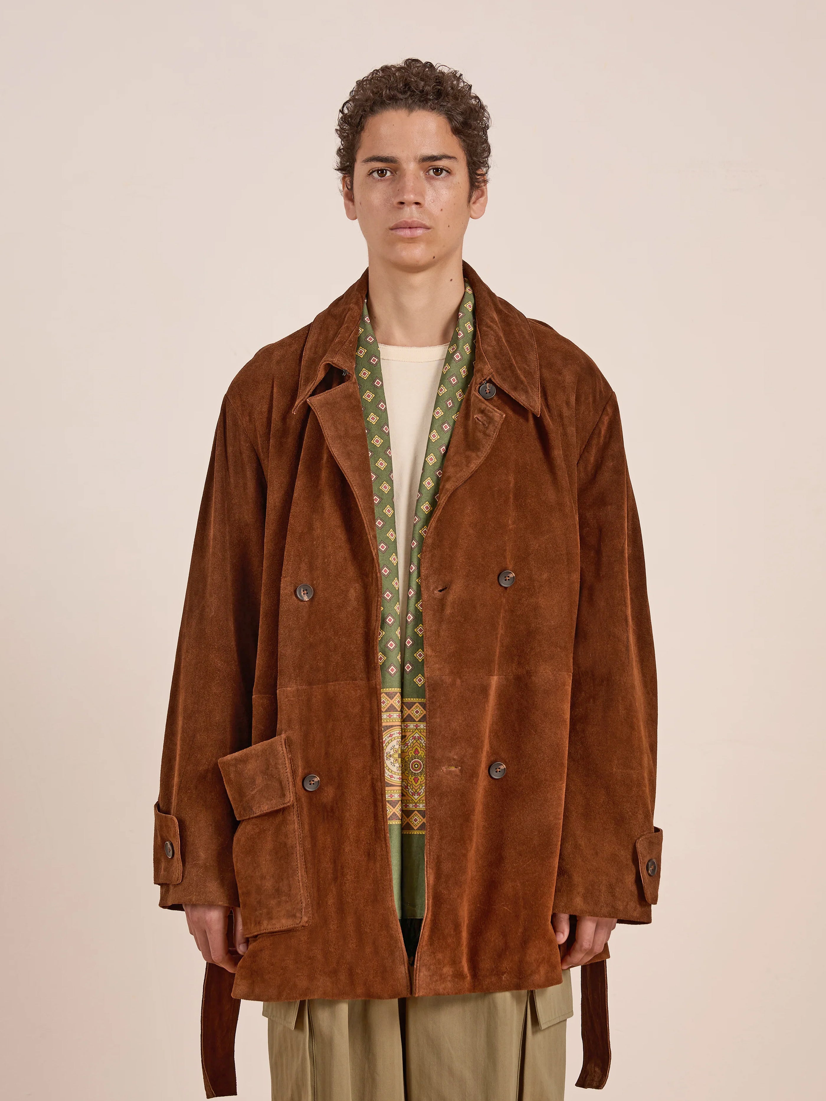 A person wears the FOUND Double Breasted Suede Leather Jacket with a relaxed unisex fit over a patterned scarf and light shirt, standing against a plain background.