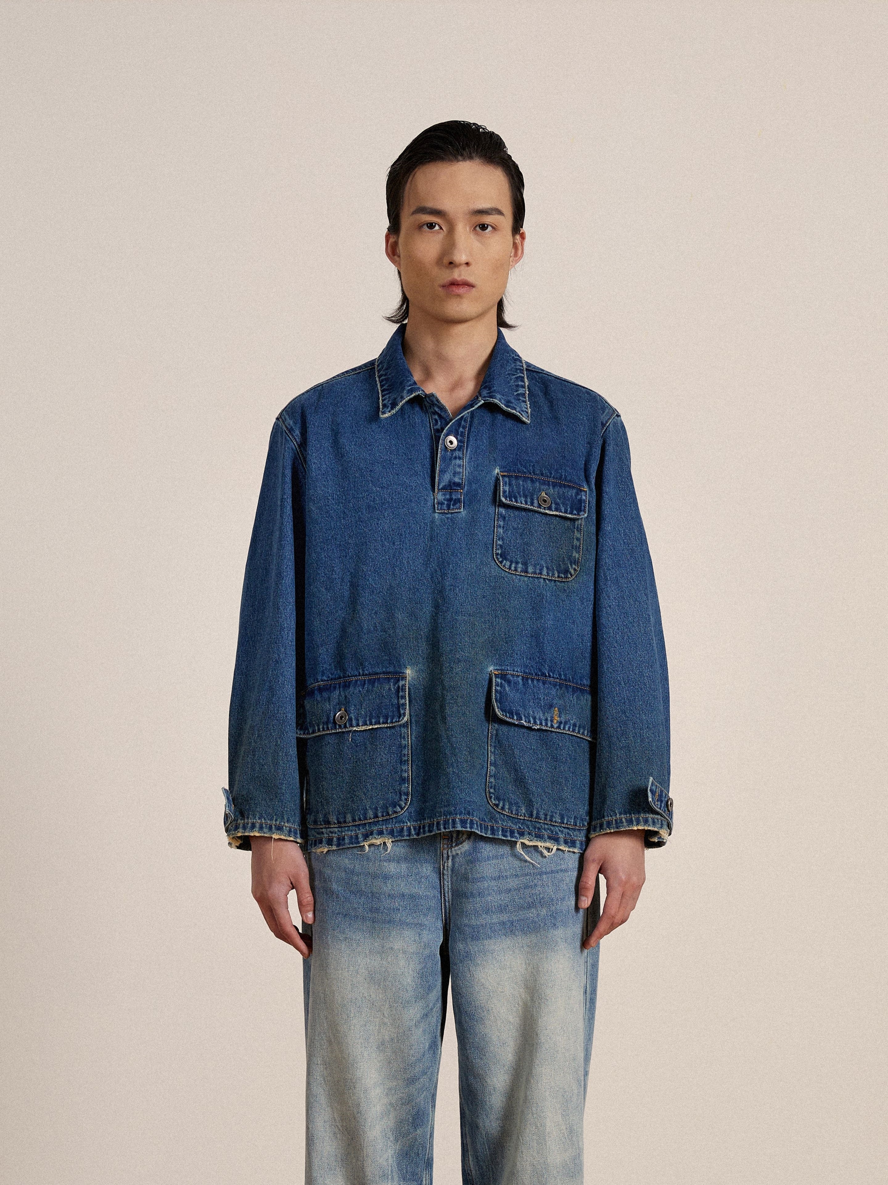 A man in a studio wearing a Found denim jacket and jeans made of premium Azin Denim fabric, standing against a pale background, looking directly at the camera.