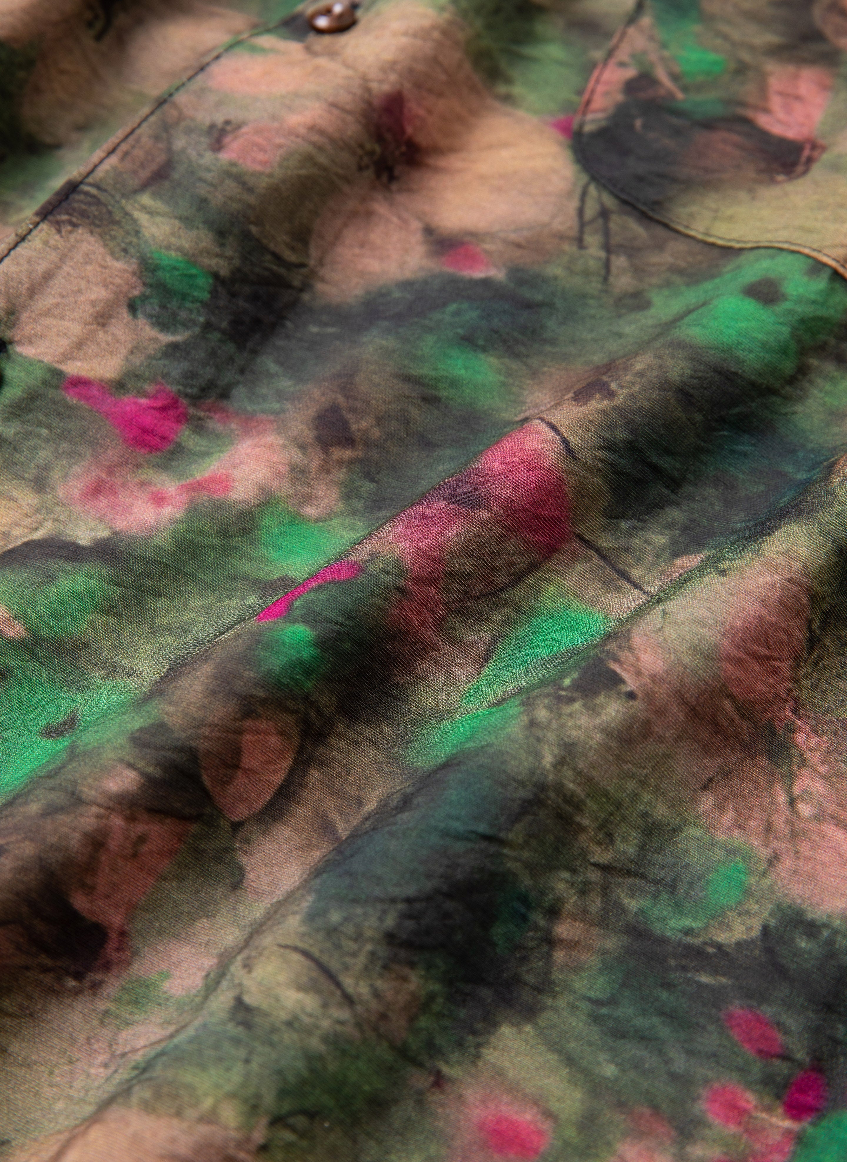 Close-up of the Charlot LS Camp Shirt by FOUND, showcasing a fabric with an abstract, multicolored pattern featuring green, pink, brown, and black hues reminiscent of a watercolor floral design.