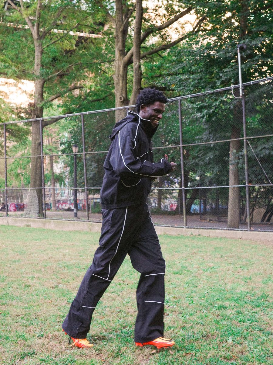 Wearing Found’s Arena Stripe Track Pants, featuring a comfy adjustable waistband, someone strolls through a park—making these unisex pants perfect for active days outdoors.