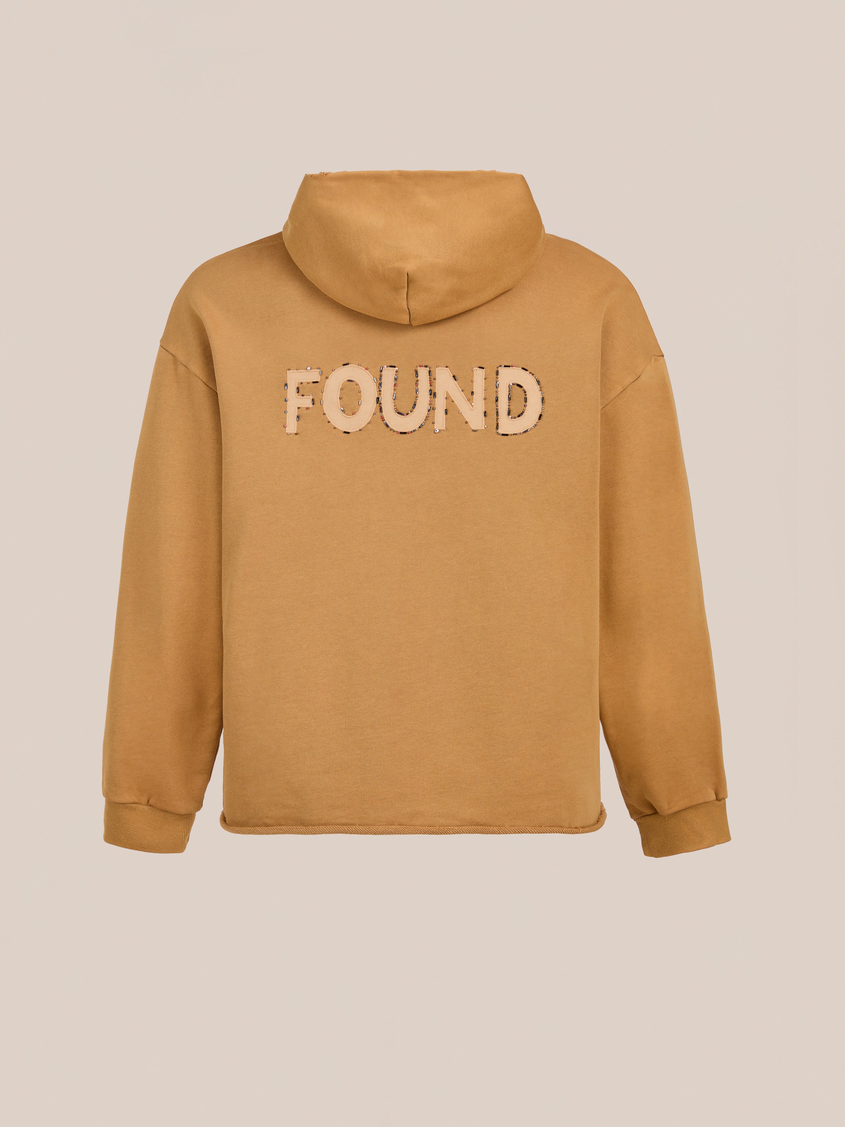 The Beadwork Logo Hoodie by FOUND is a tan vintage-style hoodie crafted from soft French terry cotton, with the brand's name boldly displayed across the back.