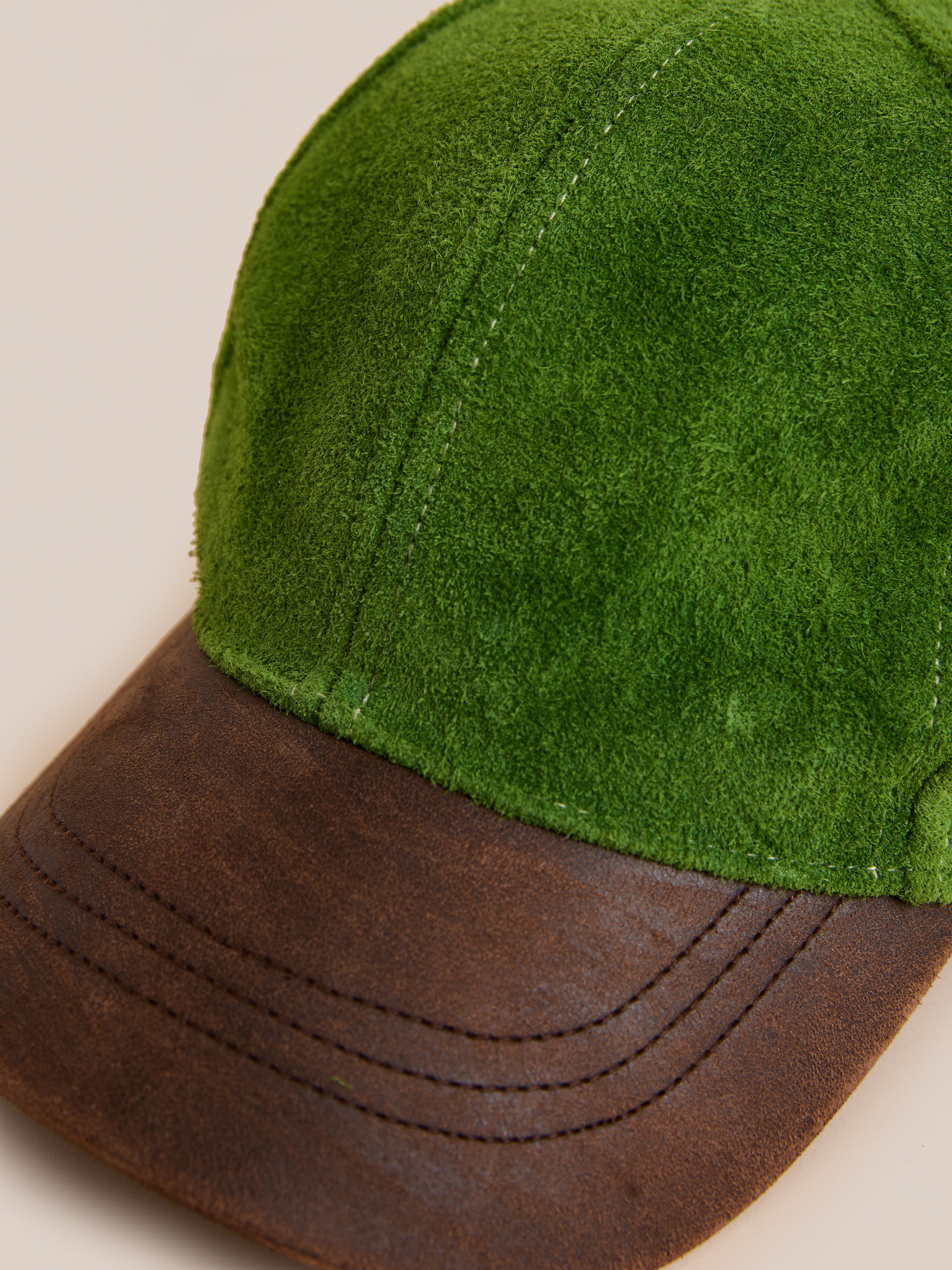 The Found Suede Leather Contrast Distressed Cap features green suede and a distressed leather brim, displayed against a neutral background.
