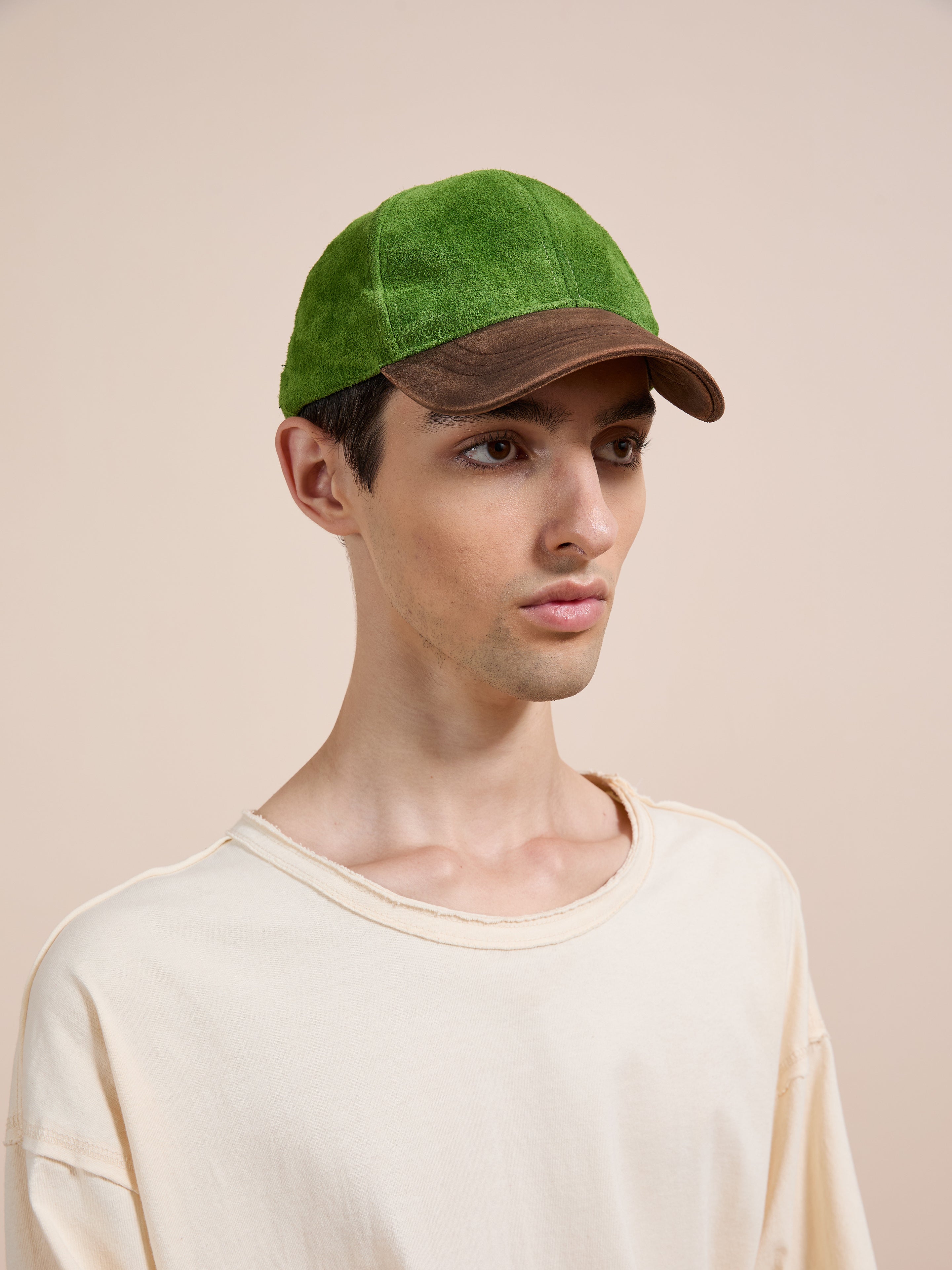 A person wearing a light beige shirt and the Found Suede Leather Contrast Distressed Cap stands against a plain beige background.