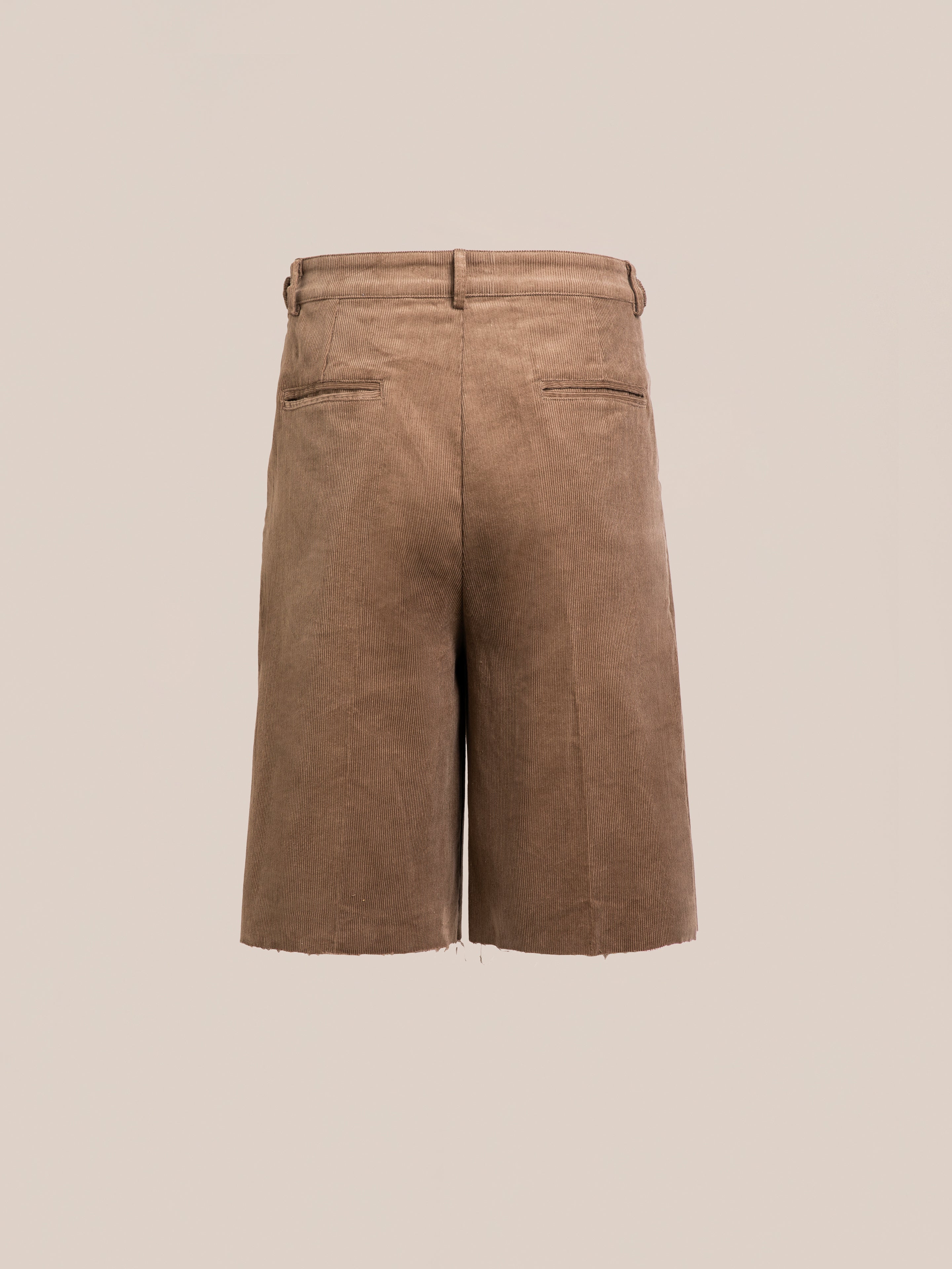 Back view of FOUND Corduroy Pleated Trouser Shorts in brown, featuring a unisex relaxed fit, belt loops, and two welt pockets, shown on a plain beige background.