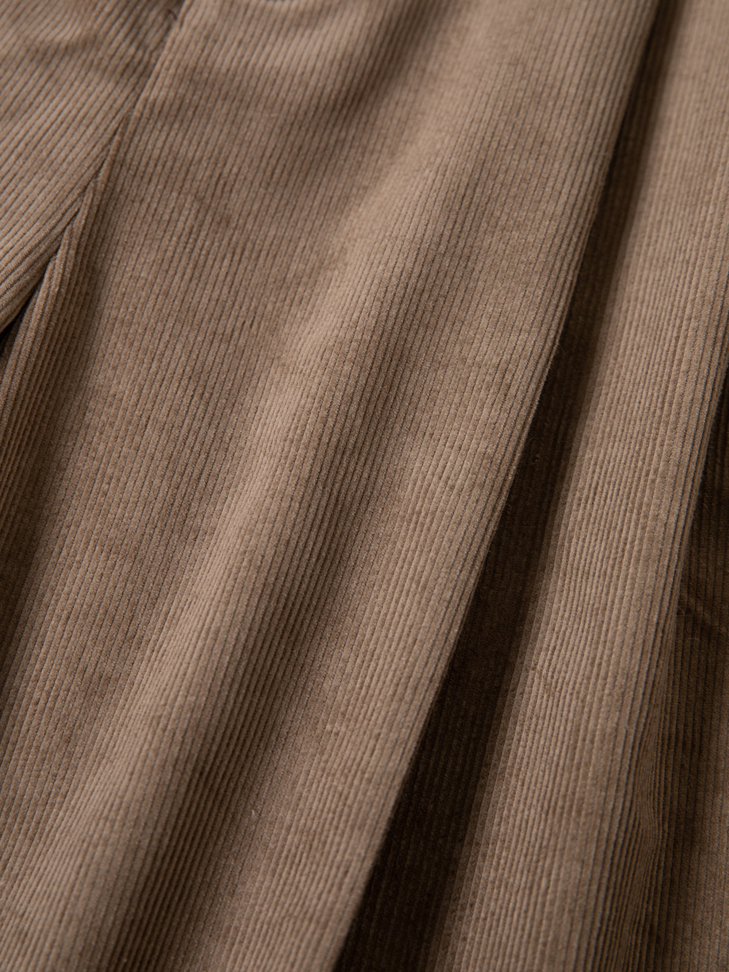 Close-up of FOUND Corduroy Pleated Trouser Shorts, showcasing their light brown color, signature vertical ridges, and relaxed unisex fit.