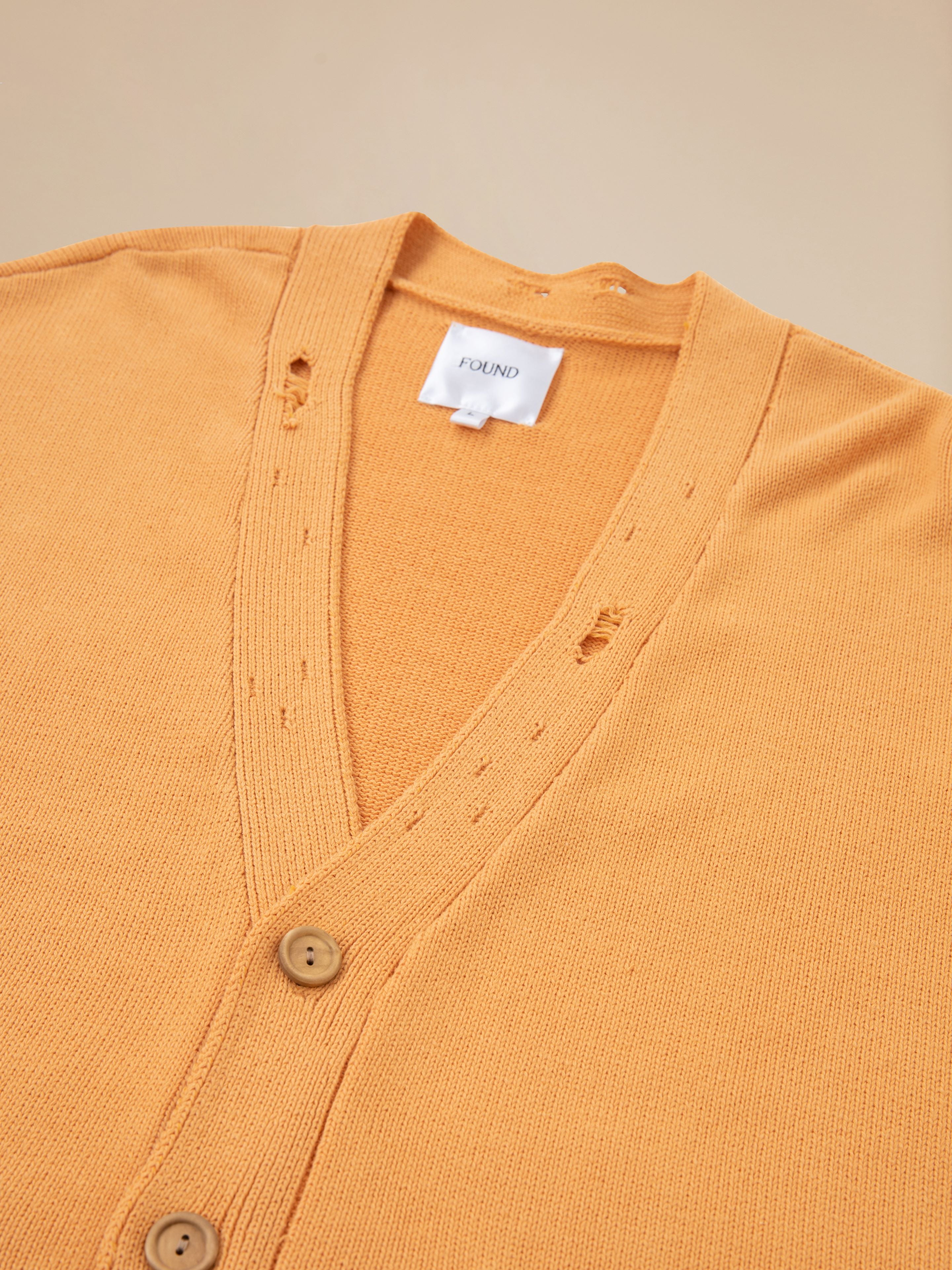 A Cadmium Distressed Cardigan by Found with buttons on the front.