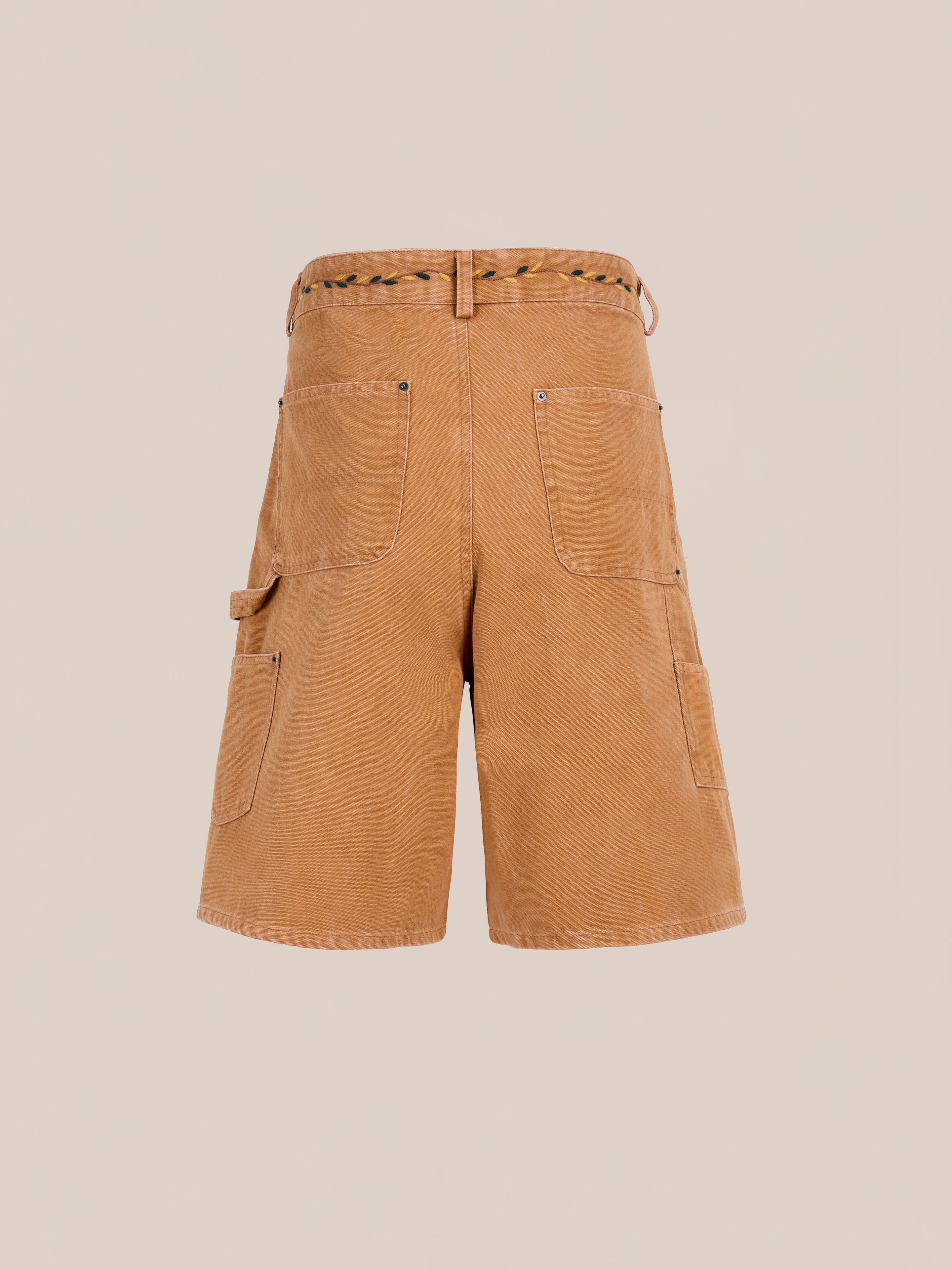 Rear view of Found Canvas Embroidered Shorts in tan, featuring large back pockets, a side tool pocket, and a woven belt, shown against a plain light background.