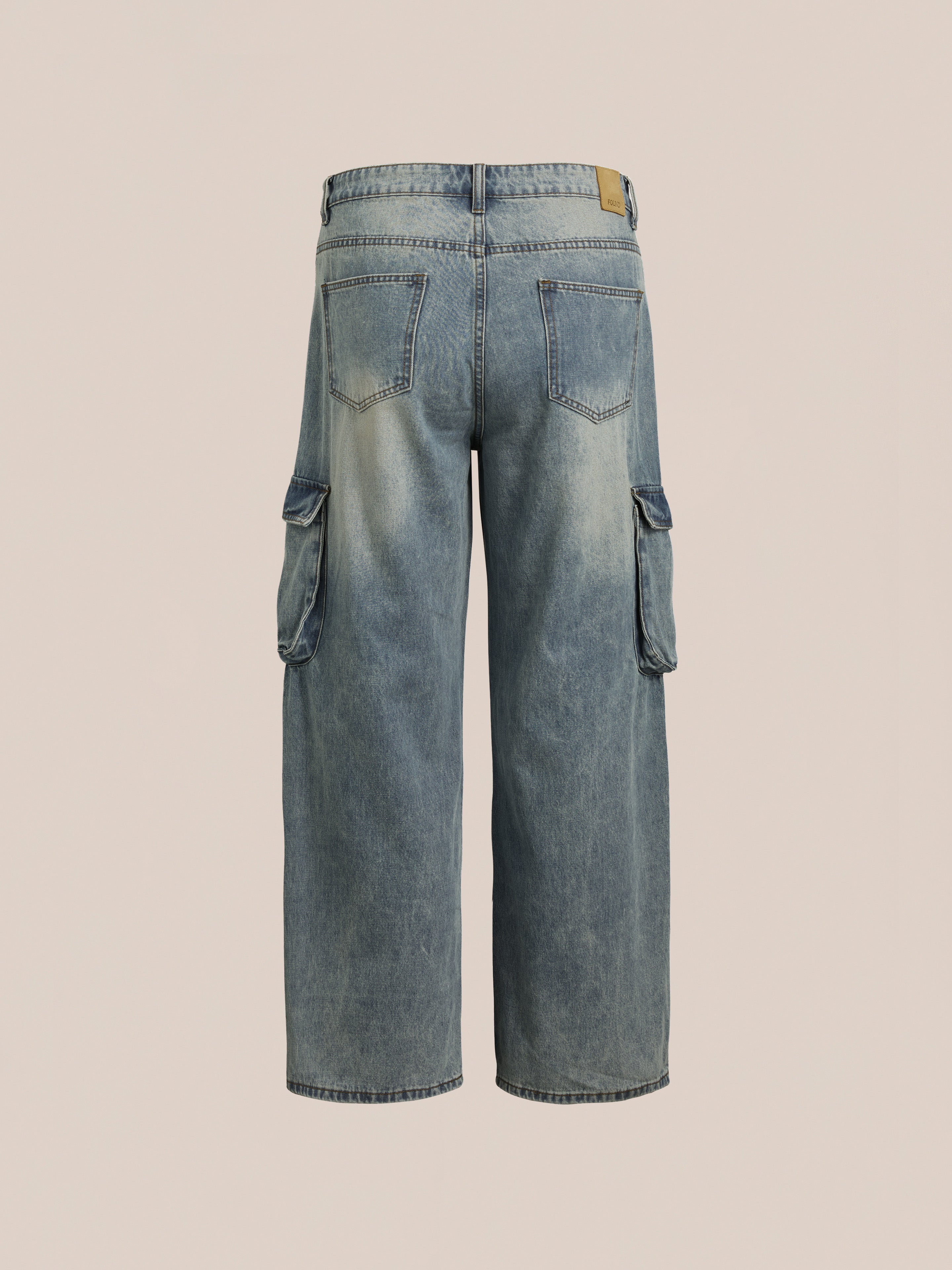 Back view of FOUND's Cargo Jeans, light blue with a relaxed fit, featuring side pockets and a faded wash that highlights workwear durability on a neutral background.