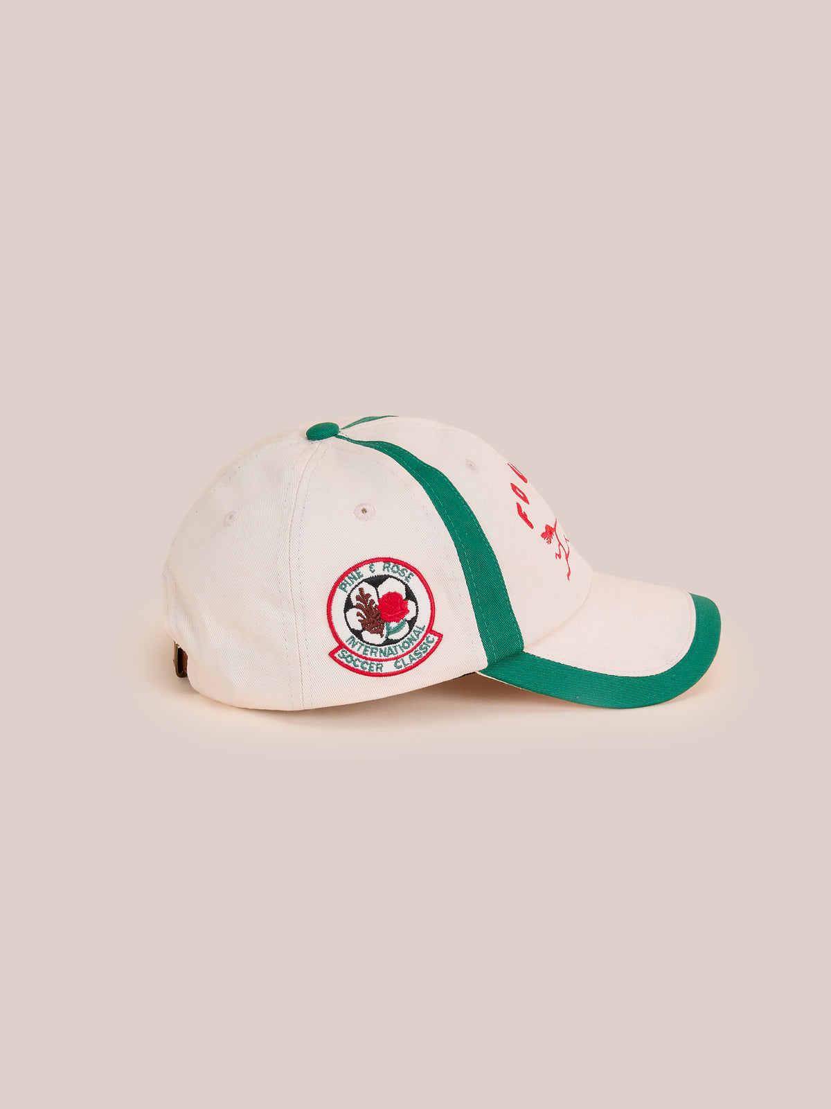 The Crestline Racing Cap by Found is a beige and green vintage club cap with a side embroidered patch of a dog and “Double Dog Sports Club” text.