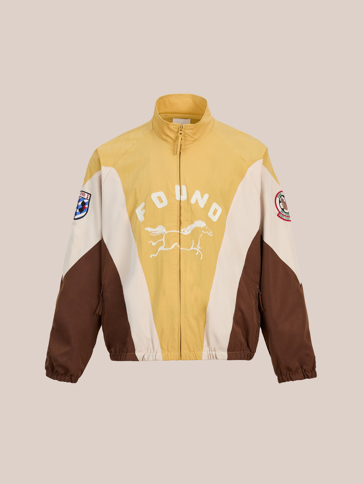 Crestline Sport Zip Jacket by FOUND: yellow, cream & brown colorblocking, “F D UNO” text, horse graphic, and two sleeve patches; bold unisex style on beige.