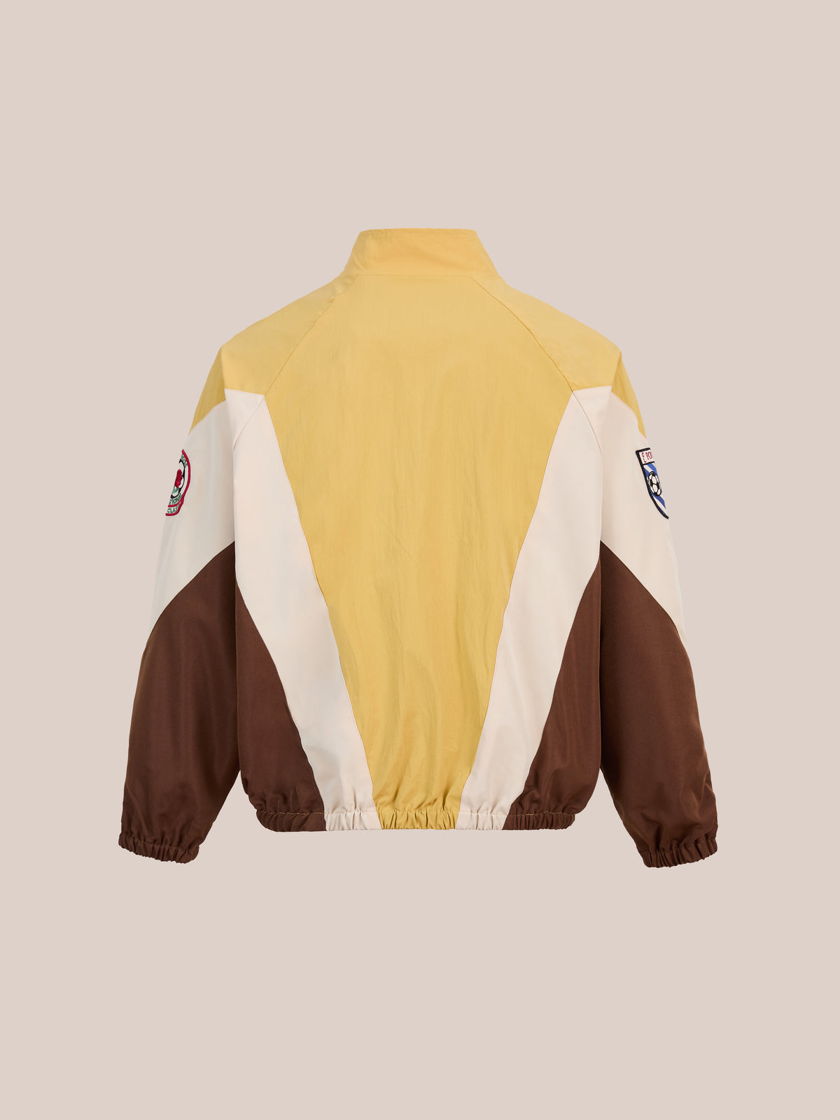 Back view of the FOUND Crestline Sport Zip Jacket in yellow, brown, and beige color-blocking with elastic waistband and sleeve patches, shown on a neutral background.