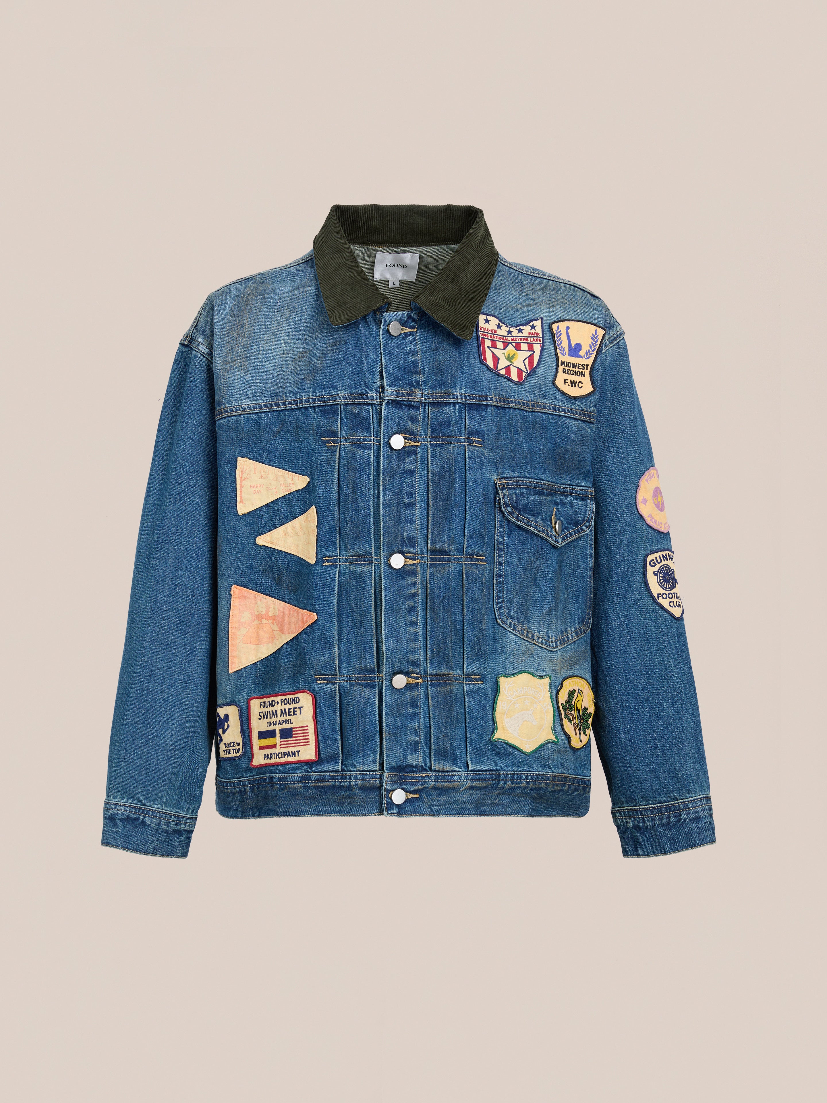 The FOUND Denim Patchwork Jacket features a vintage wash, black collar, front buttons, and colorful embroidered patches on the front, sleeves, and shoulders. Its unisex relaxed fit is inspired by classic workwear for effortless style.