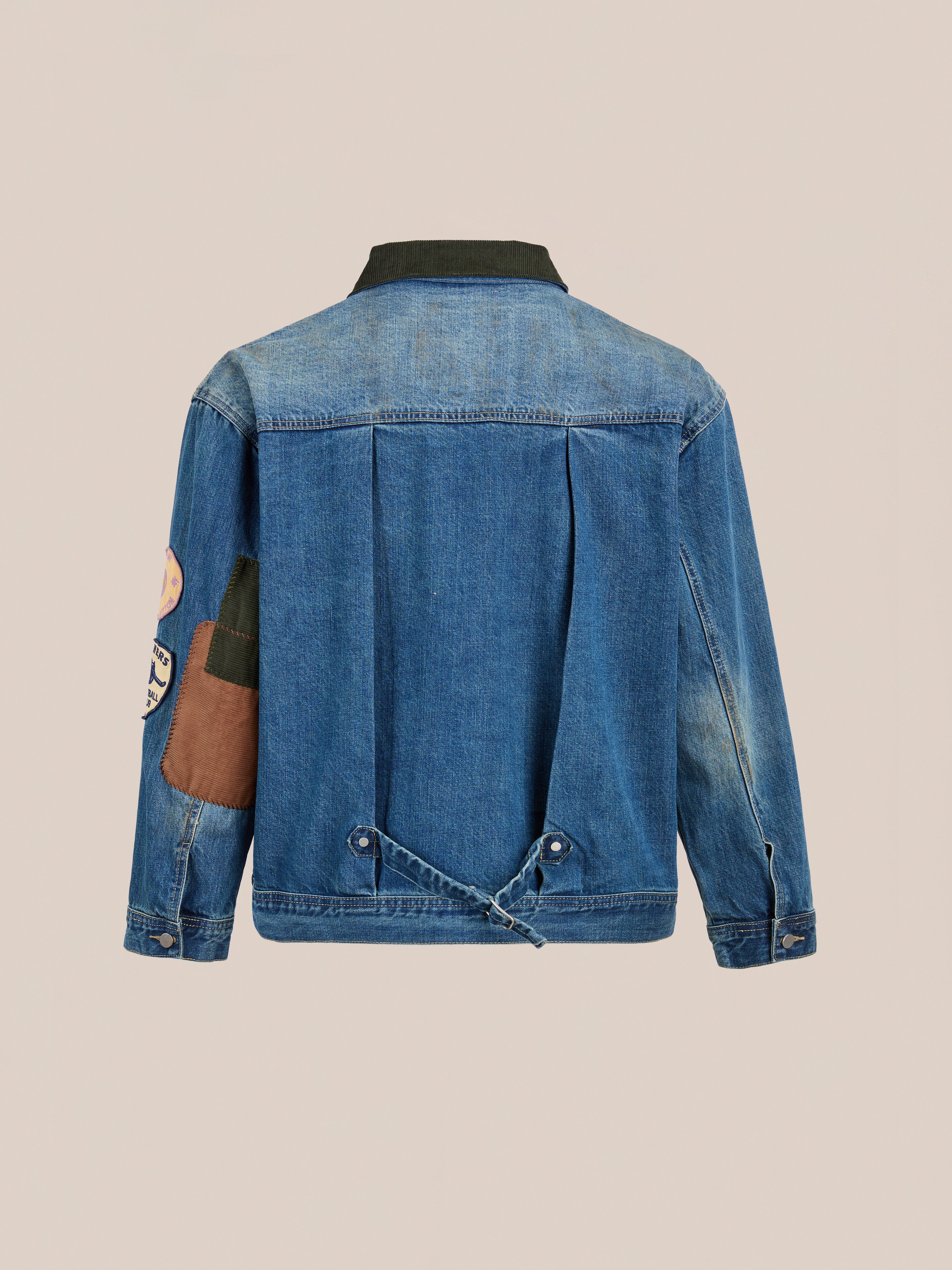 Back view of the FOUND Denim Patchwork Jacket, a unisex relaxed fit with vintage-washed denim, dark collar, brown and green patch on the right sleeve, and adjustable lower back straps.