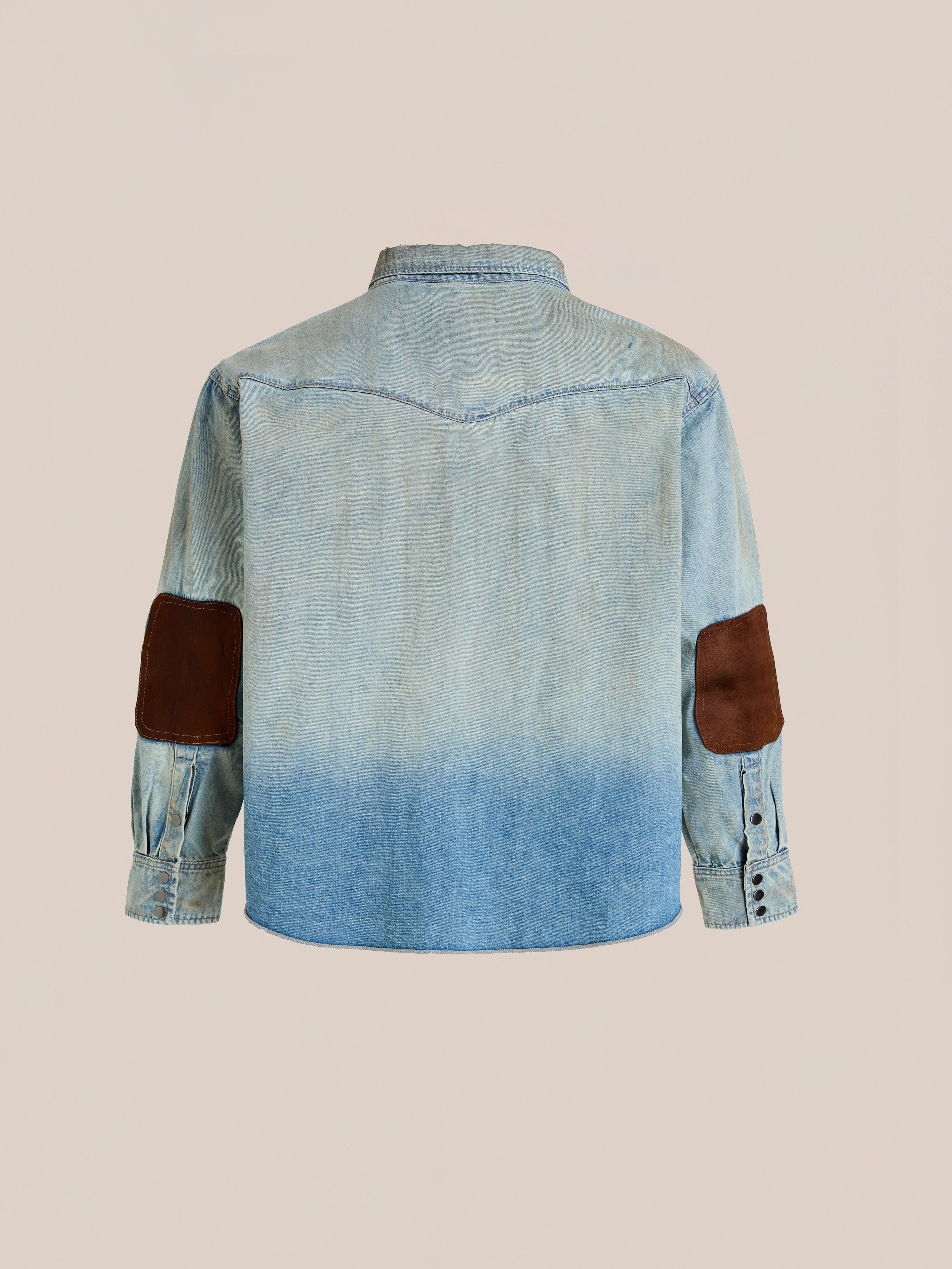 The FOUND Denim Western Snap Button Shirt in light blue features brown suede elbow patches and a western yoke, shown from the back against a plain beige background.
