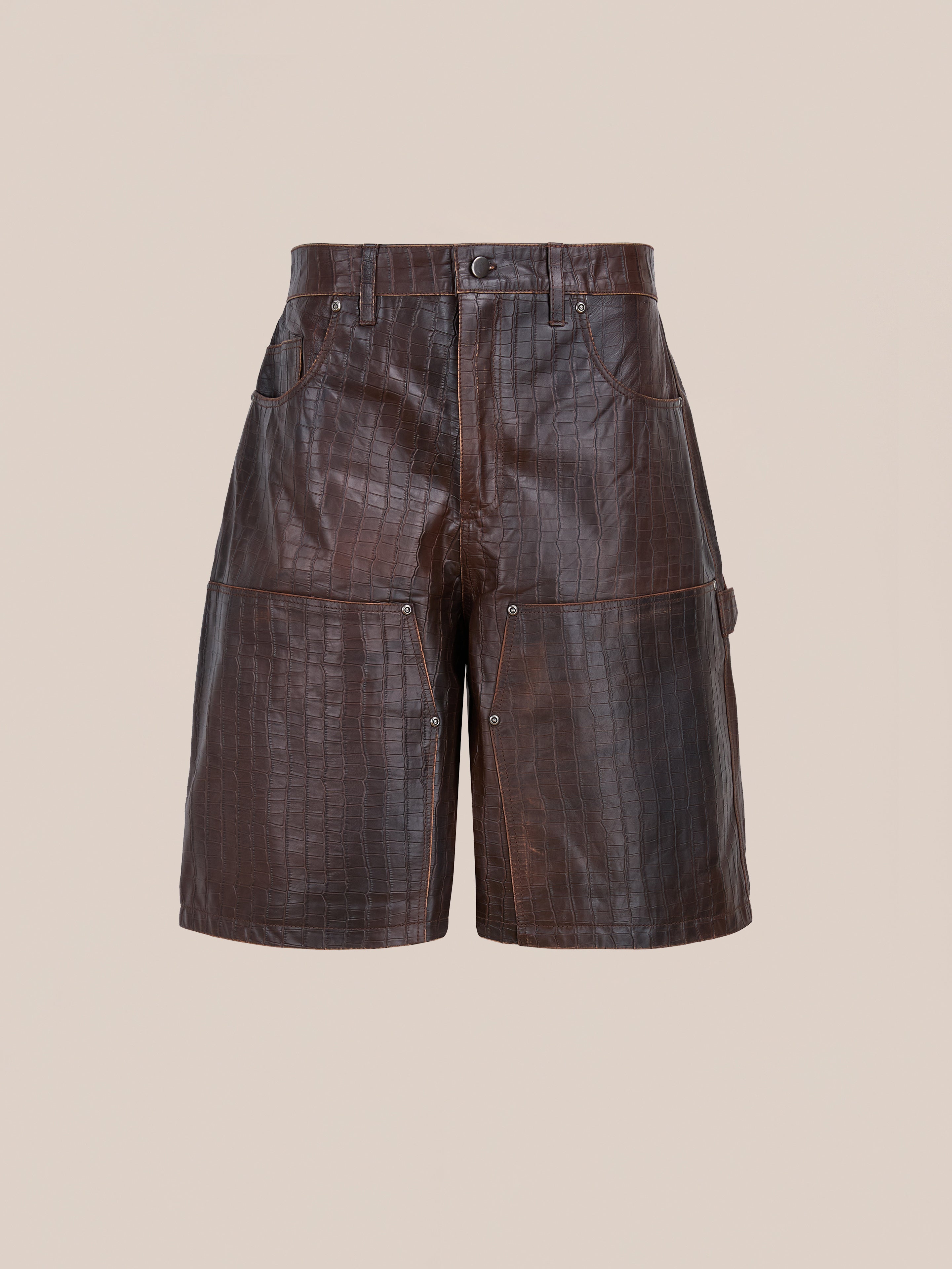 FOUND's Distressed Croc Embossed Leather Shorts feature a high waist, front and back pockets, visible stitching, and a button fly, shown on a plain beige background.