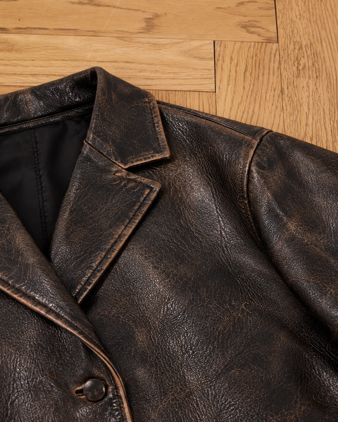 A close-up of the FOUND Distressed Leather Blazer with collar and button detail on a wooden floor—ideal for those who love a classic look.