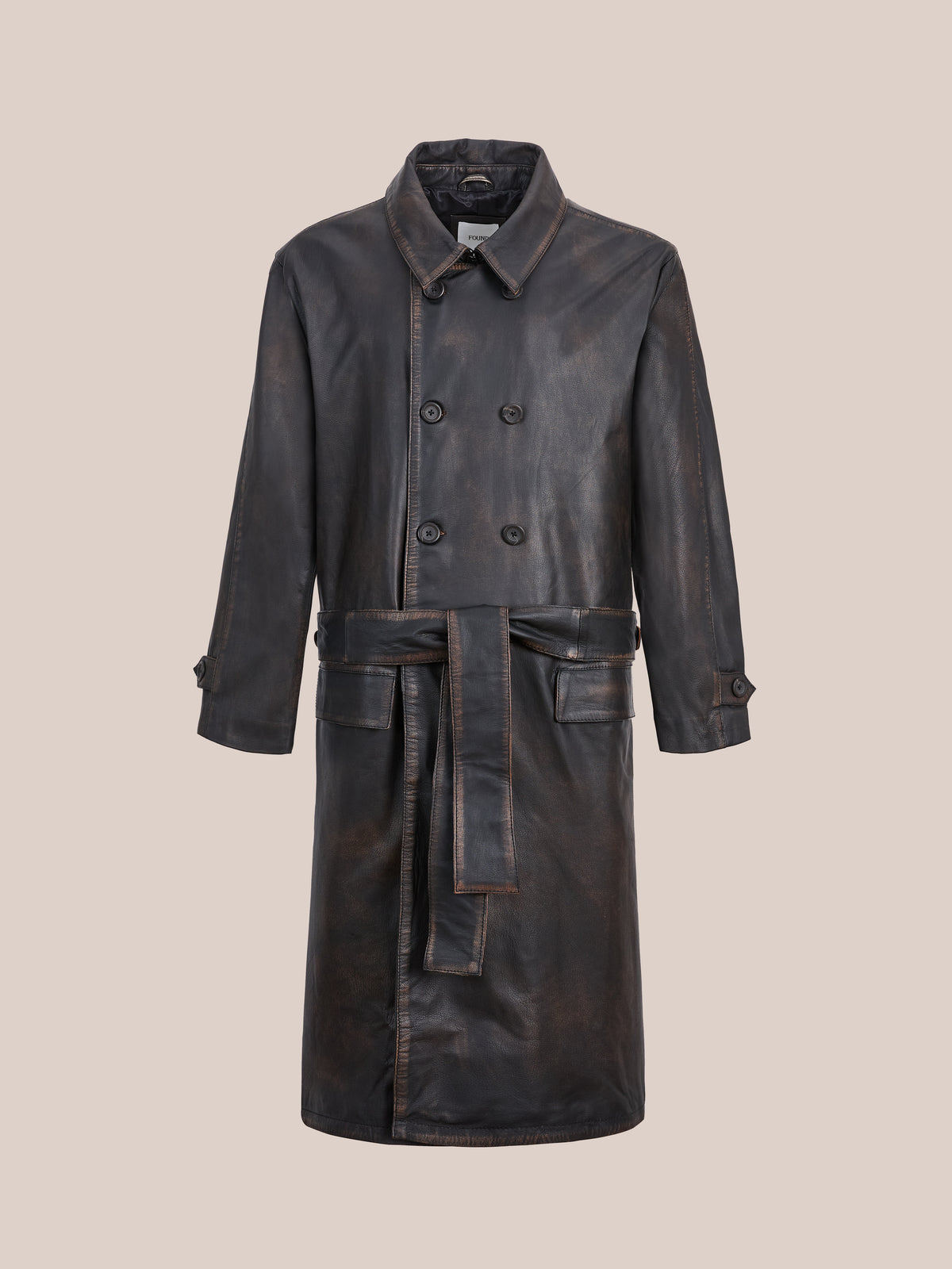 The FOUND Belted Leather Trench Coat is a long, dark brown unisex style with double-breasted buttons, a belted waist, and buttoned cuffs on a beige background.