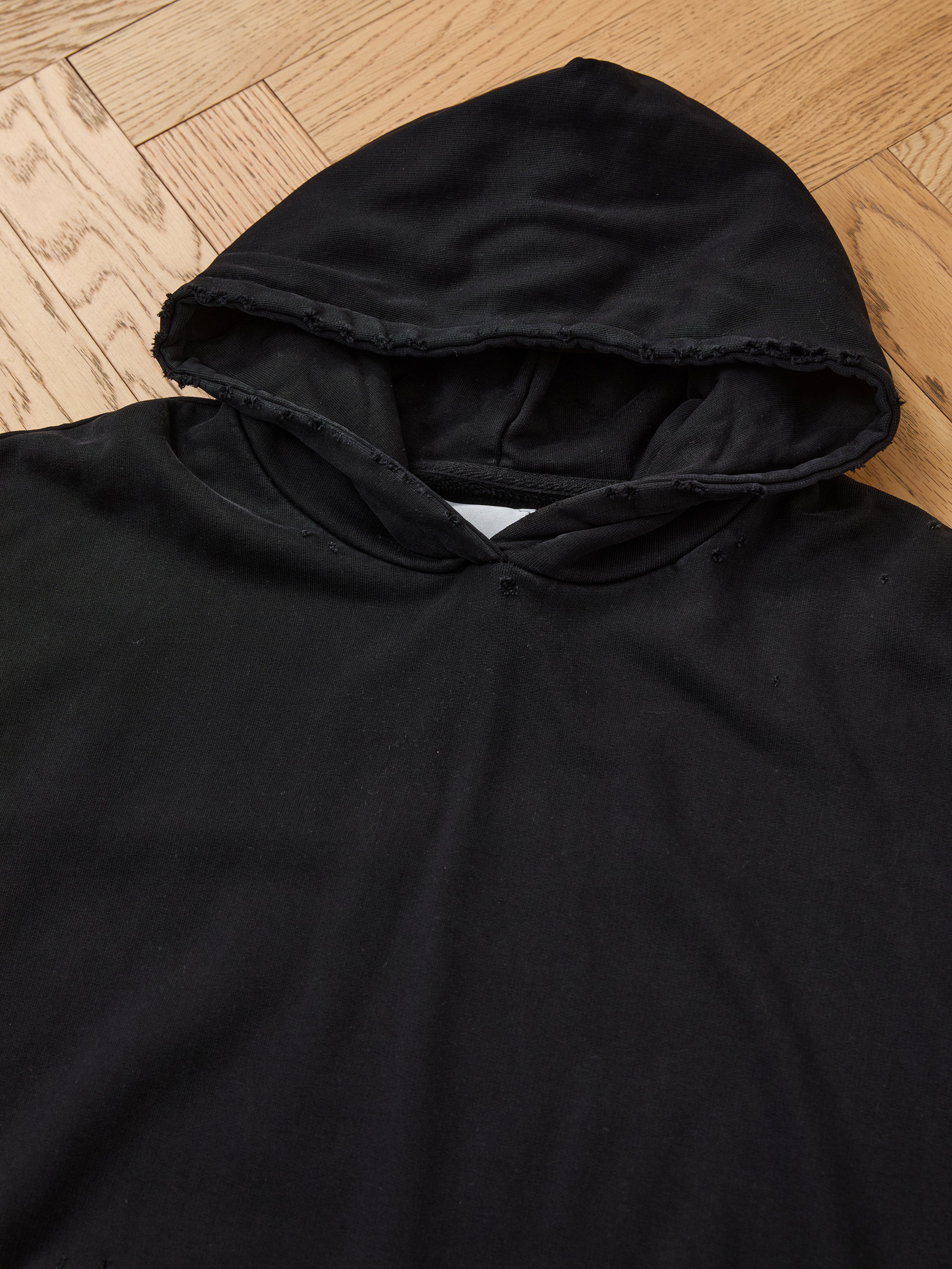 The FOUND Distressed Pullover Hoodie, featuring a vintage black look, distressed collar, and unisex relaxed fit, delivers effortless style and comfort.