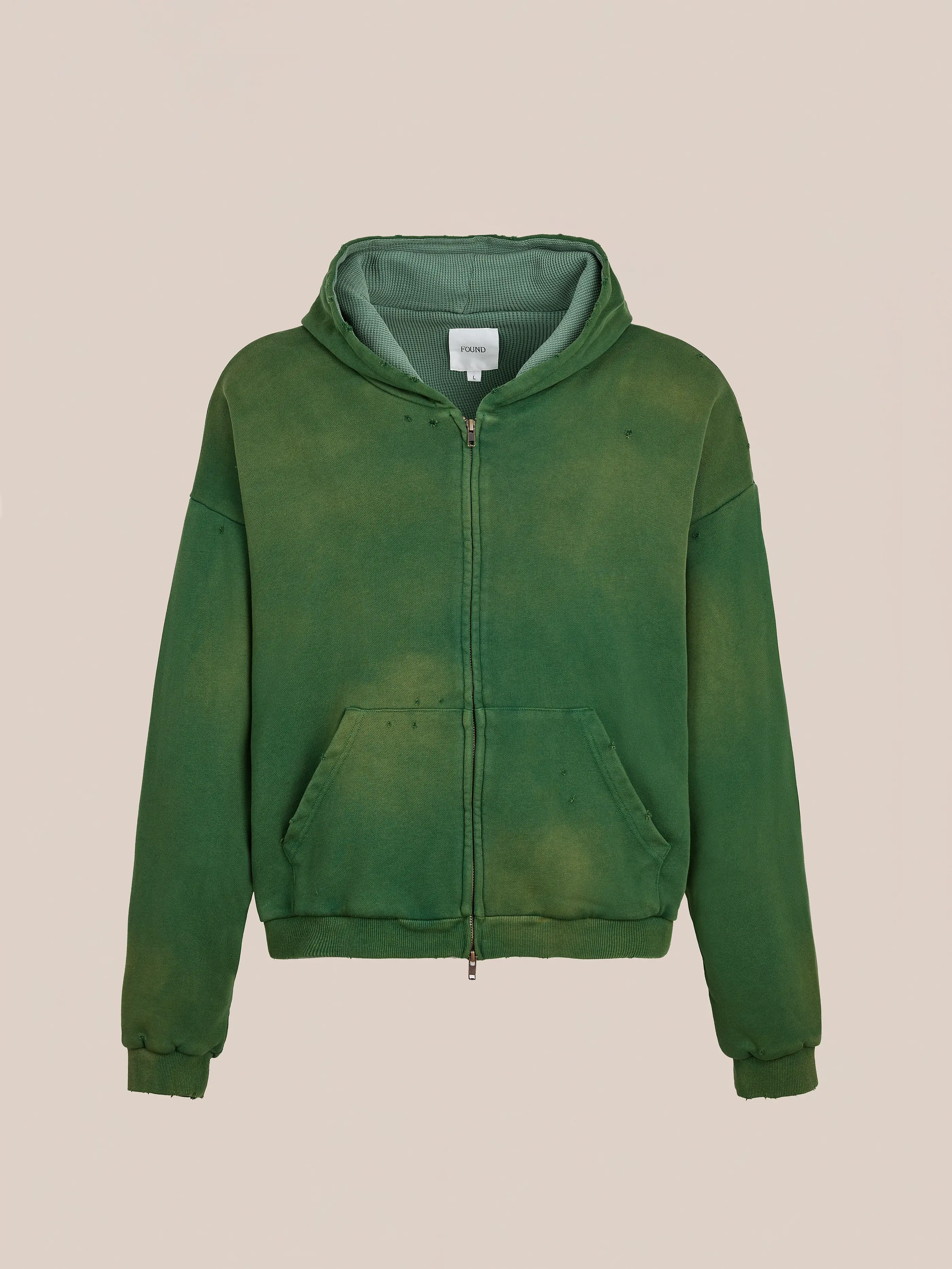 The FOUND Distressed Thermal Lined Zip Up Hoodie, a green unisex relaxed fit style with front pocket, ribbed cuffs, and hood, is displayed against a plain beige background.