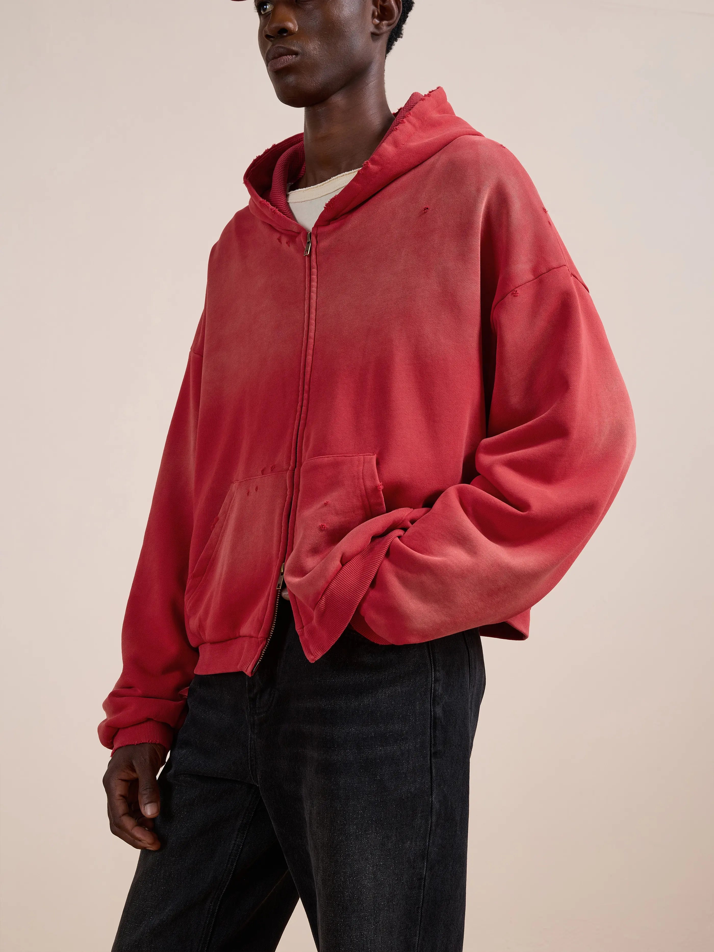A person wears the FOUND Distressed Thermal Lined Zip Up Hoodie in faded red over a white shirt and black jeans, standing against a plain light background.