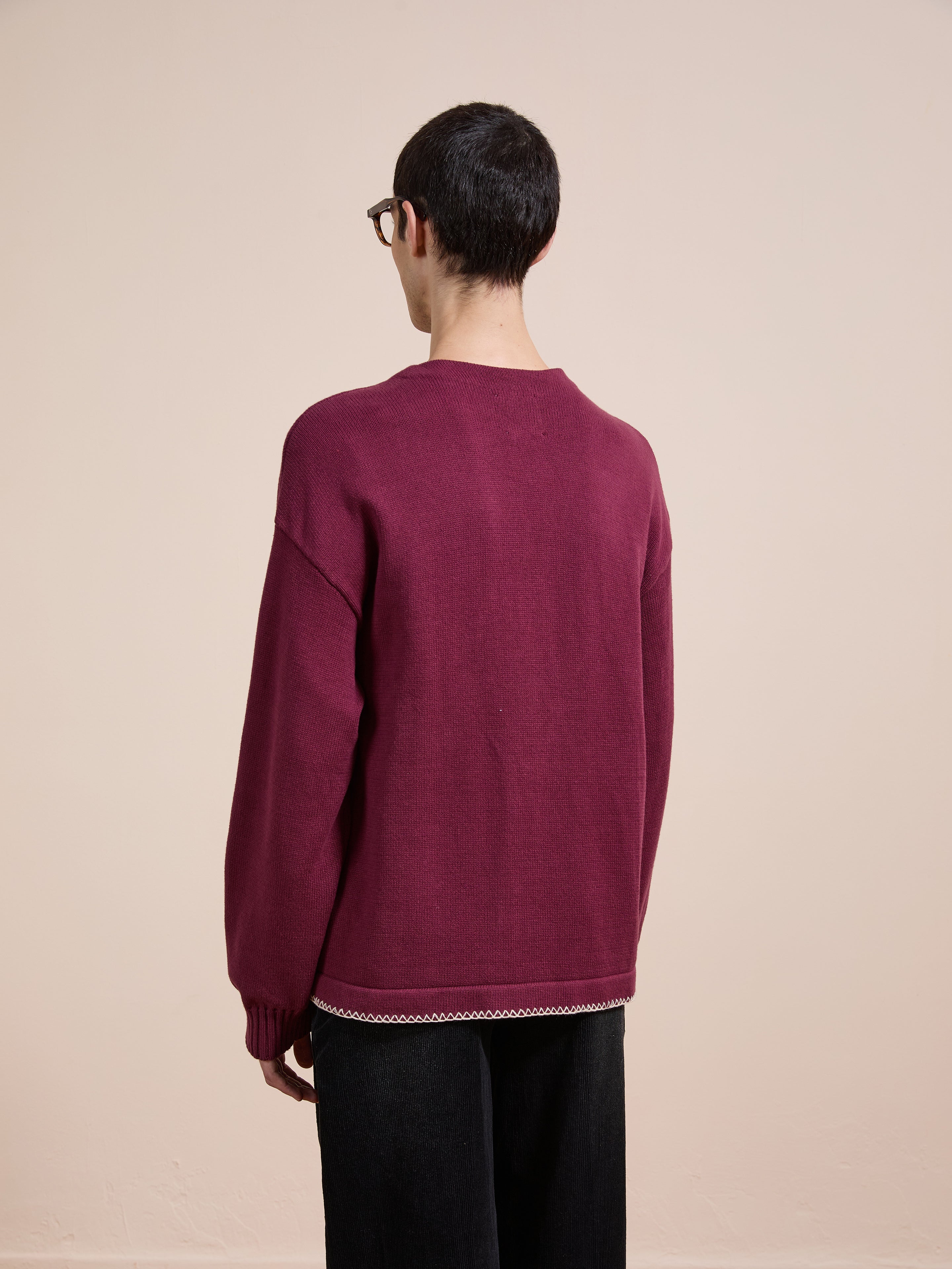 A person with short dark hair and glasses models the FOUND Double Breasted Bow Cardigan, standing with their back to the camera against a plain beige background.