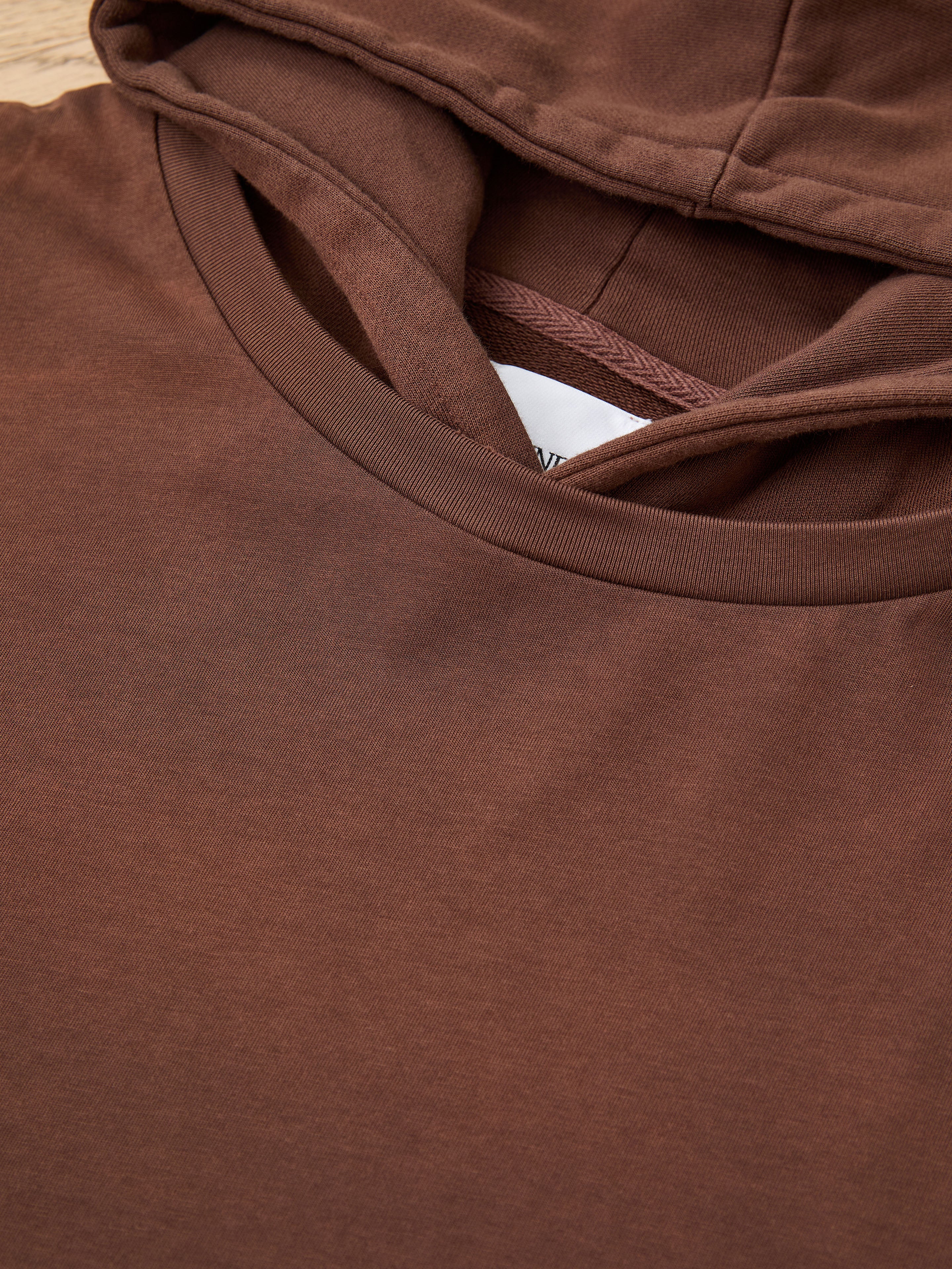 Close-up of the Found Double Layer Hoodie in brown, laid flat to show the hood, neckline, and part of the inner tag for a cozy vintage look.