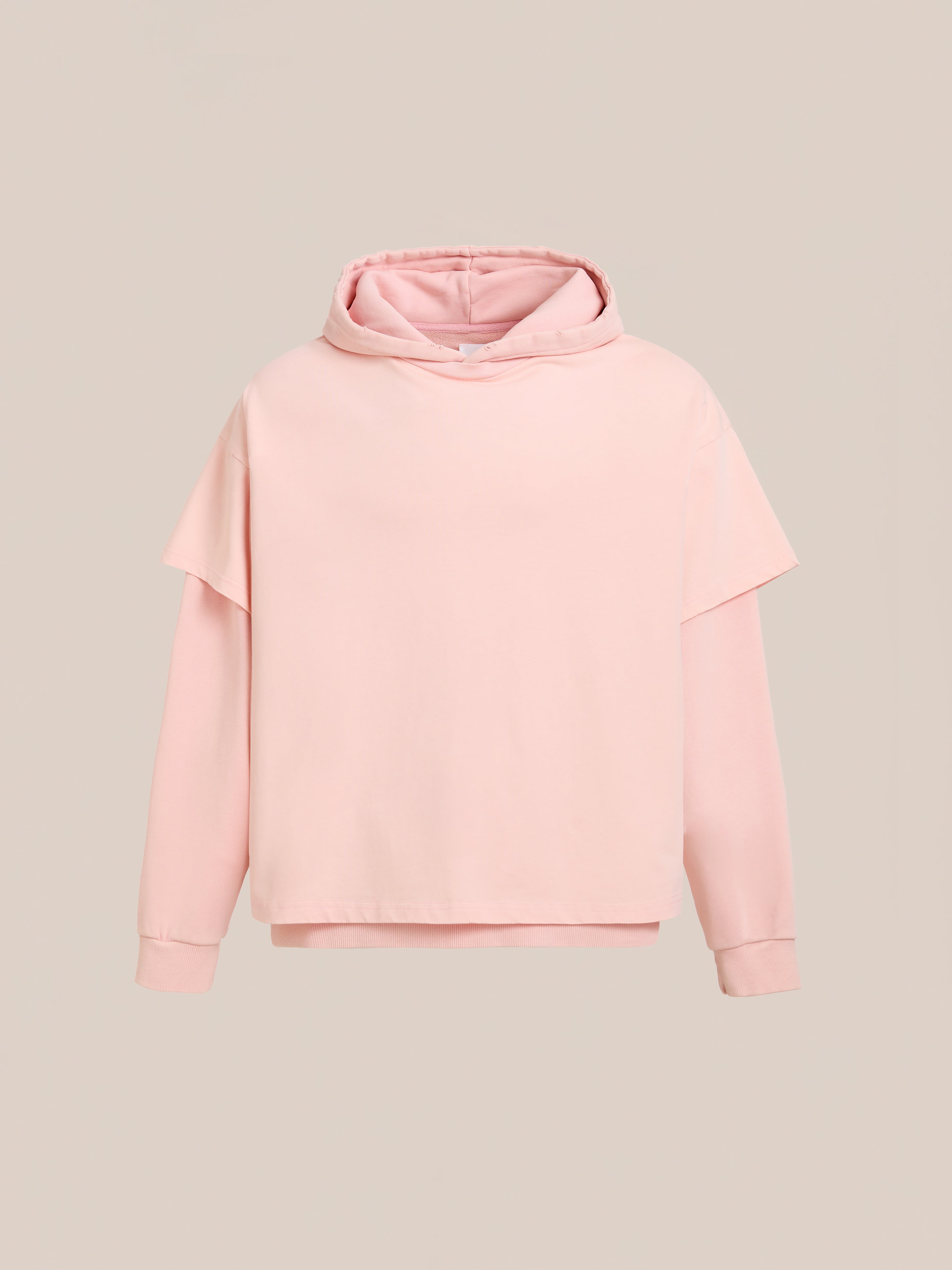 The Found Double Layer Hoodie features a light pink hue, long sleeves, and a unisex relaxed fit in soft French terry cotton, shown on a plain beige background.
