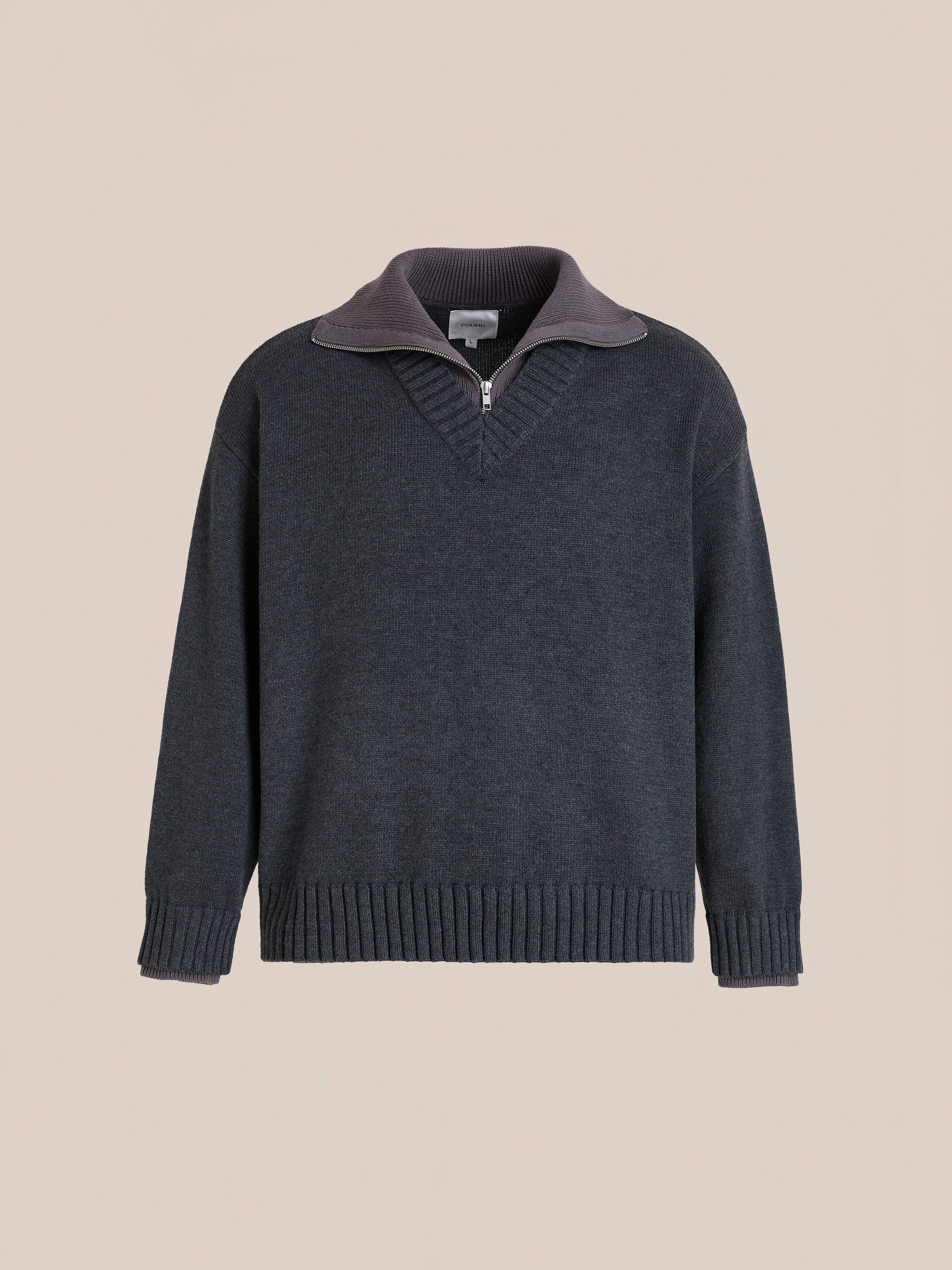 The FOUND Double Layer Sweater is a charcoal wool blend V-neck knit featuring a ribbed neckline, short front zipper, and ribbed cuffs and hem, shown against a plain beige background.