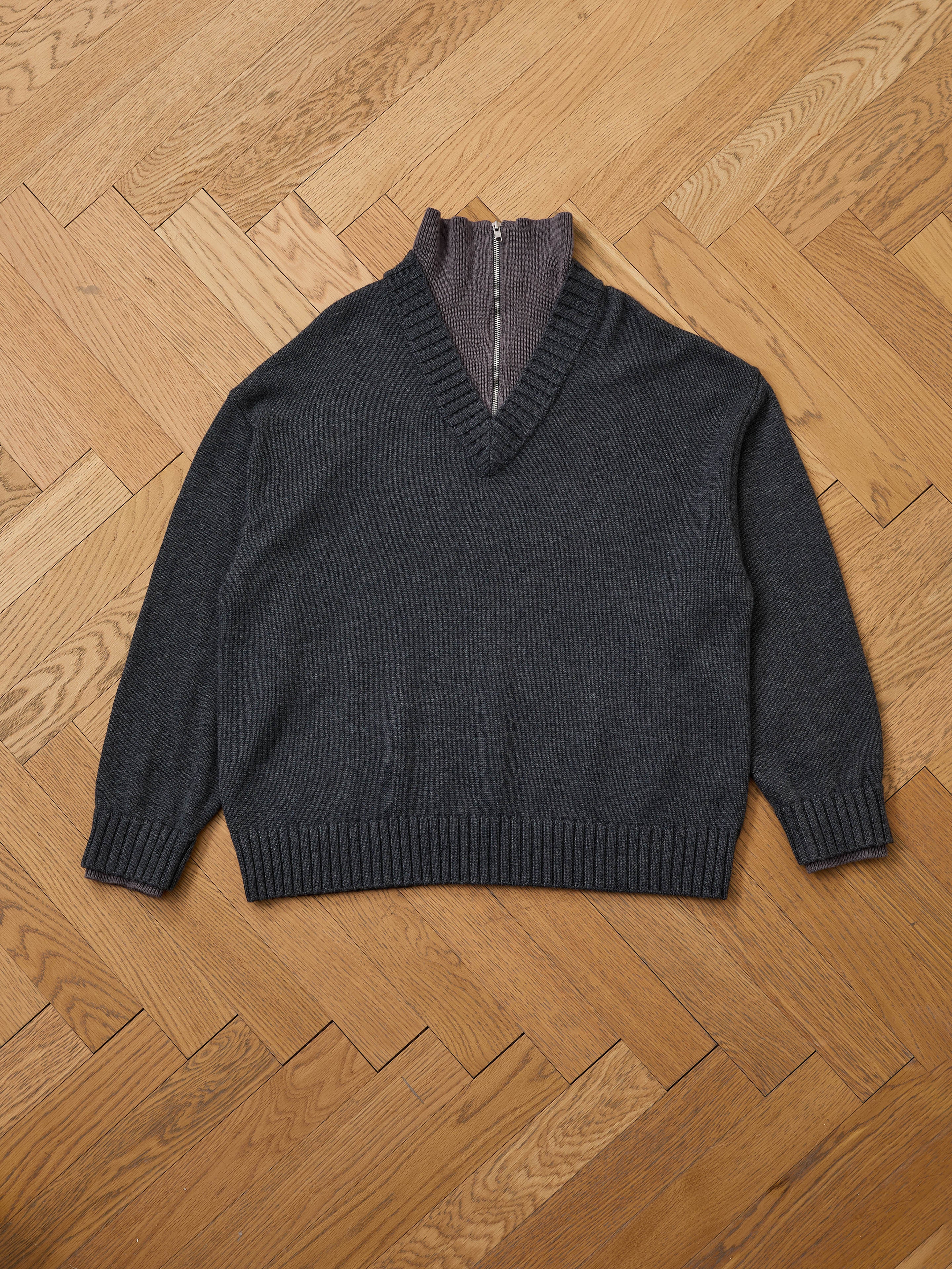 The FOUND Double Layer Sweater features a dark grey wool blend with ribbed cuffs and hem, layered over a gray zip-up mock neck shirt—ideal for cold-weather layering.
