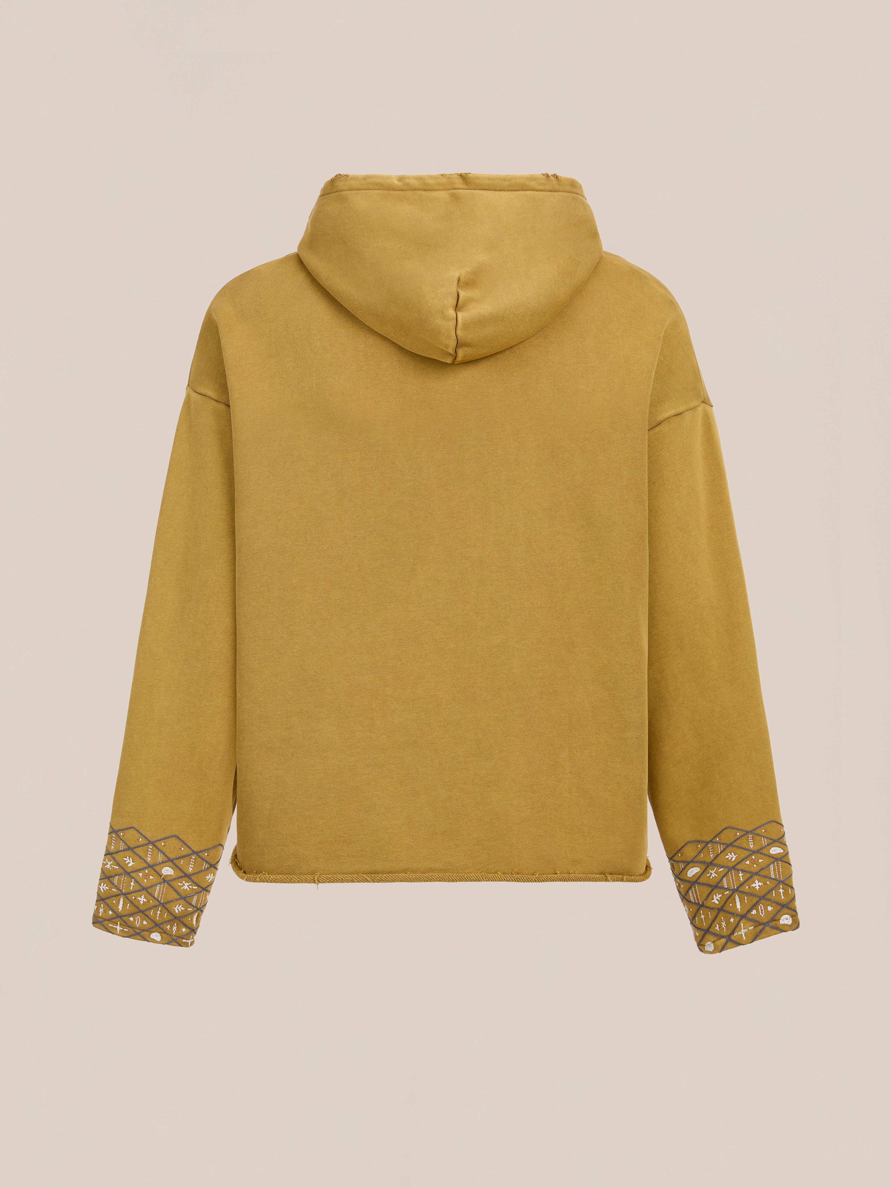 The FOUND Embroidered Border Hoodie in mustard yellow cotton is shown from the back, highlighting geometric embroidered sleeve cuffs against a plain background.