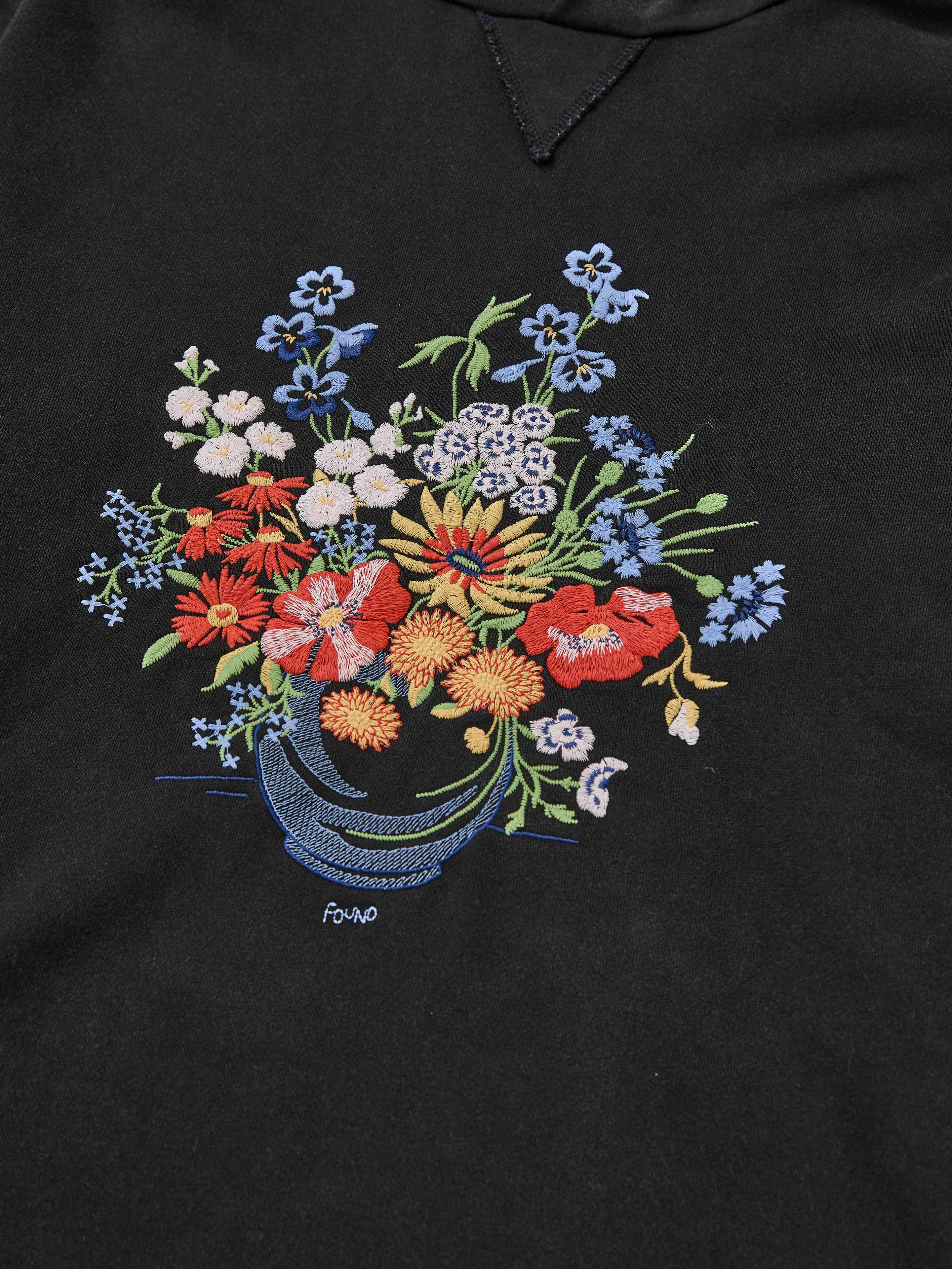 The FOUND Bouquet Flowers Hoodie features vibrant floral embroidery of a bouquet in a vase on black fabric, inspired by traditional Phulkari designs.