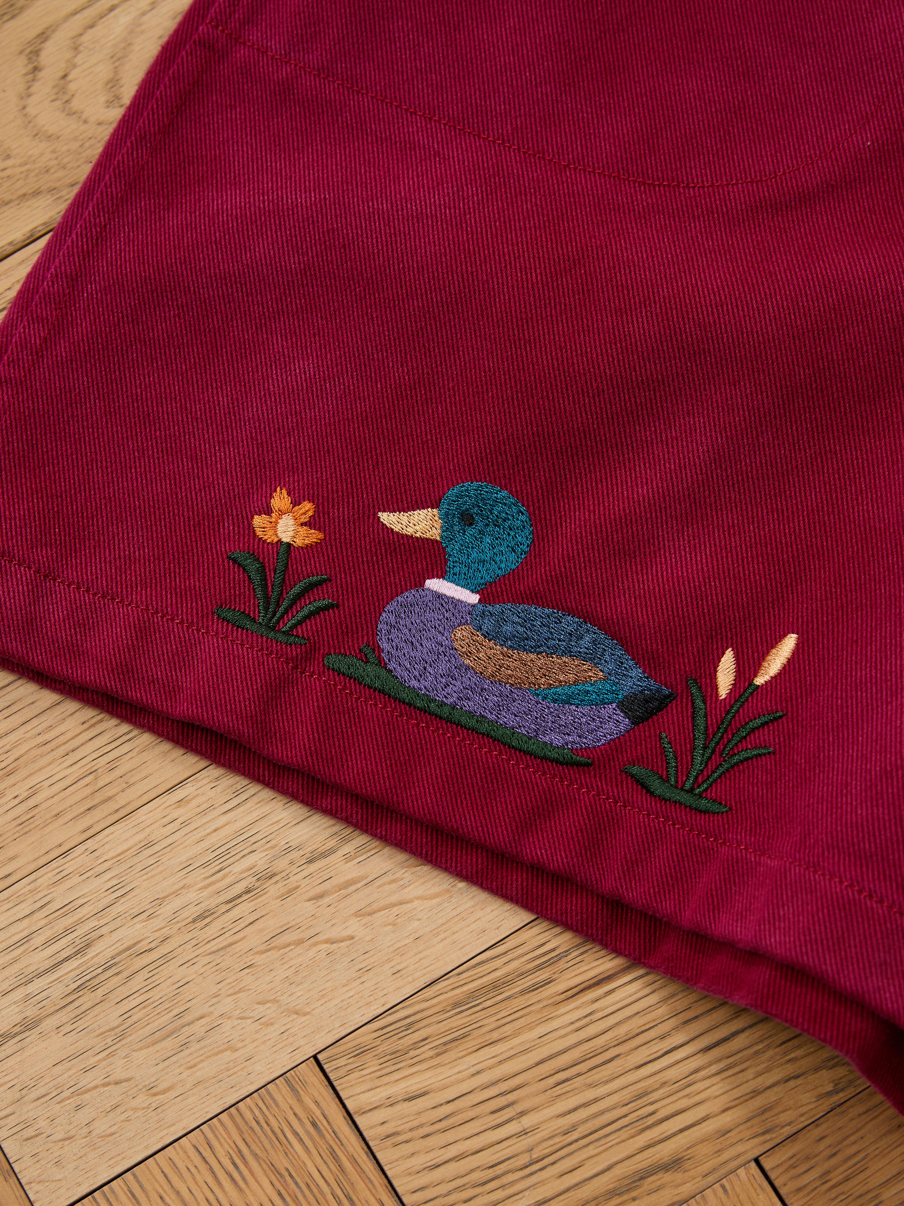 A close-up of Found's Embroidered Duck Shorts in maroon corduroy, showcasing duck, yellow flower, and cattails embroidery—ideal for vintage shorts enthusiasts.