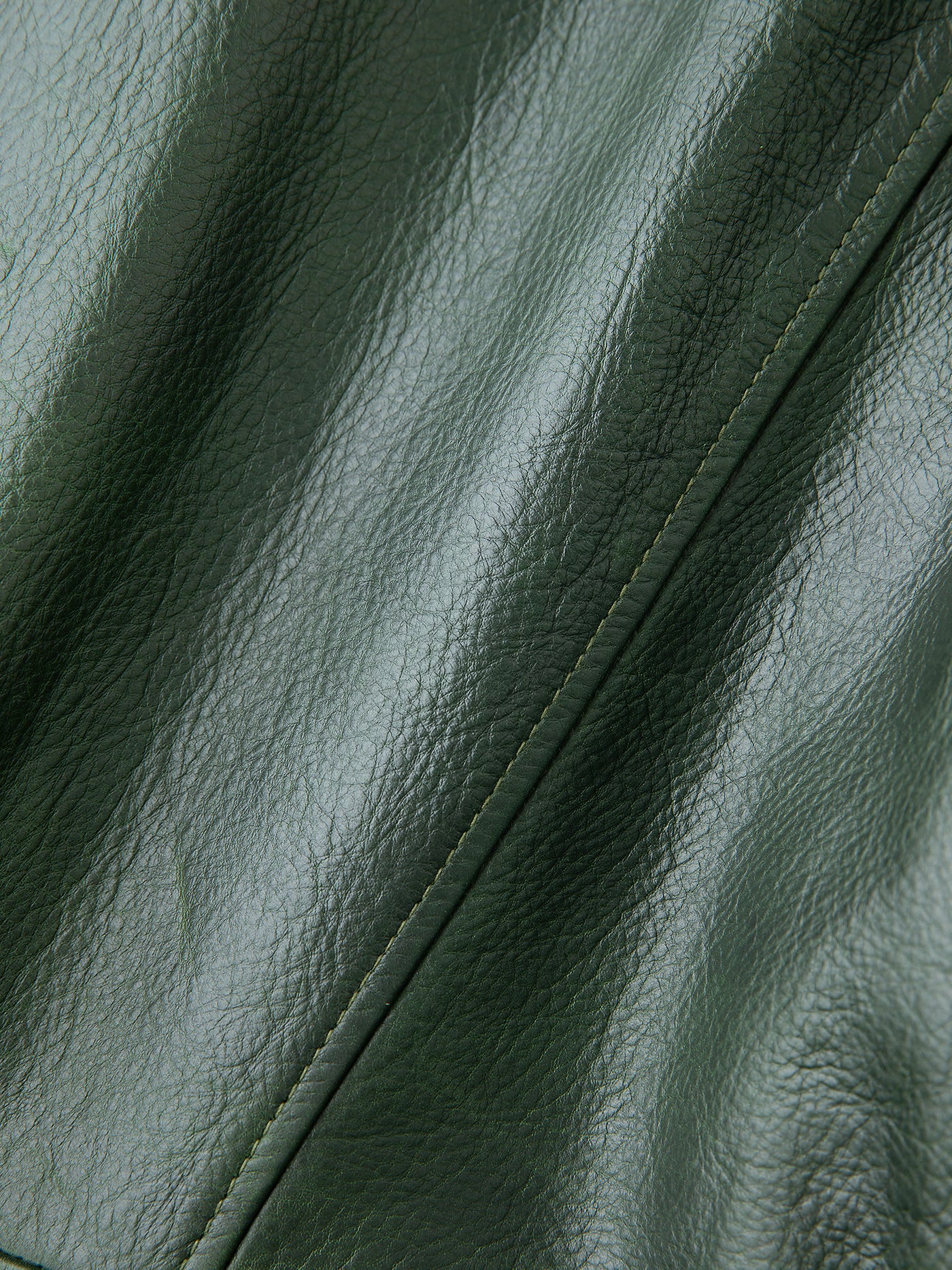 Close-up of FOUND's Leather Field Jacket in hand-distressed dark green leather with visible stitching and sheen, crafted from ethically sourced materials.